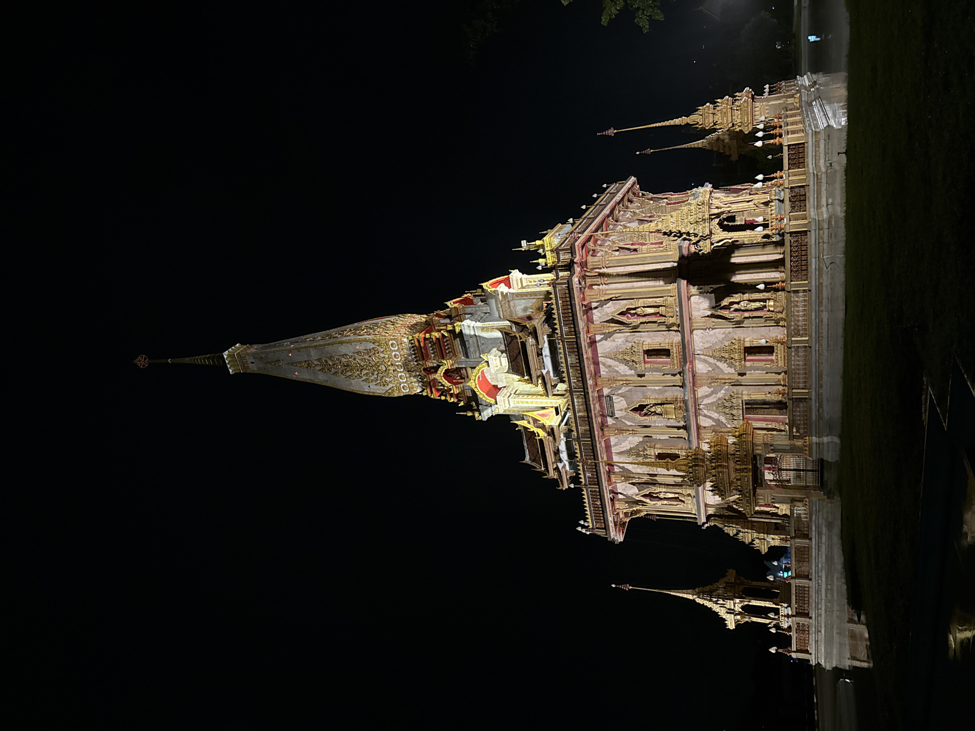Wat Chalong temple glowing at night, reflection on water