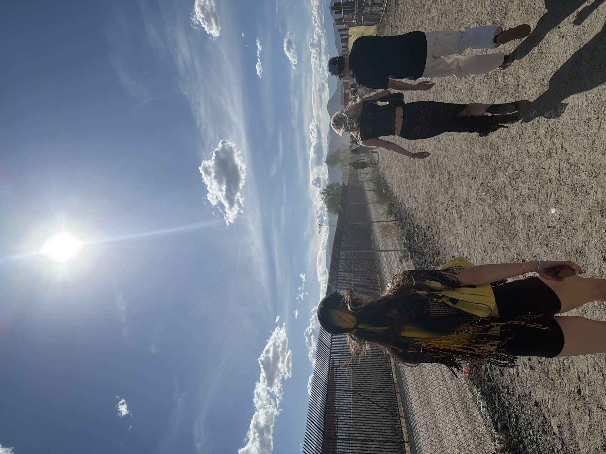 People gather near fence and tent structure in Indio