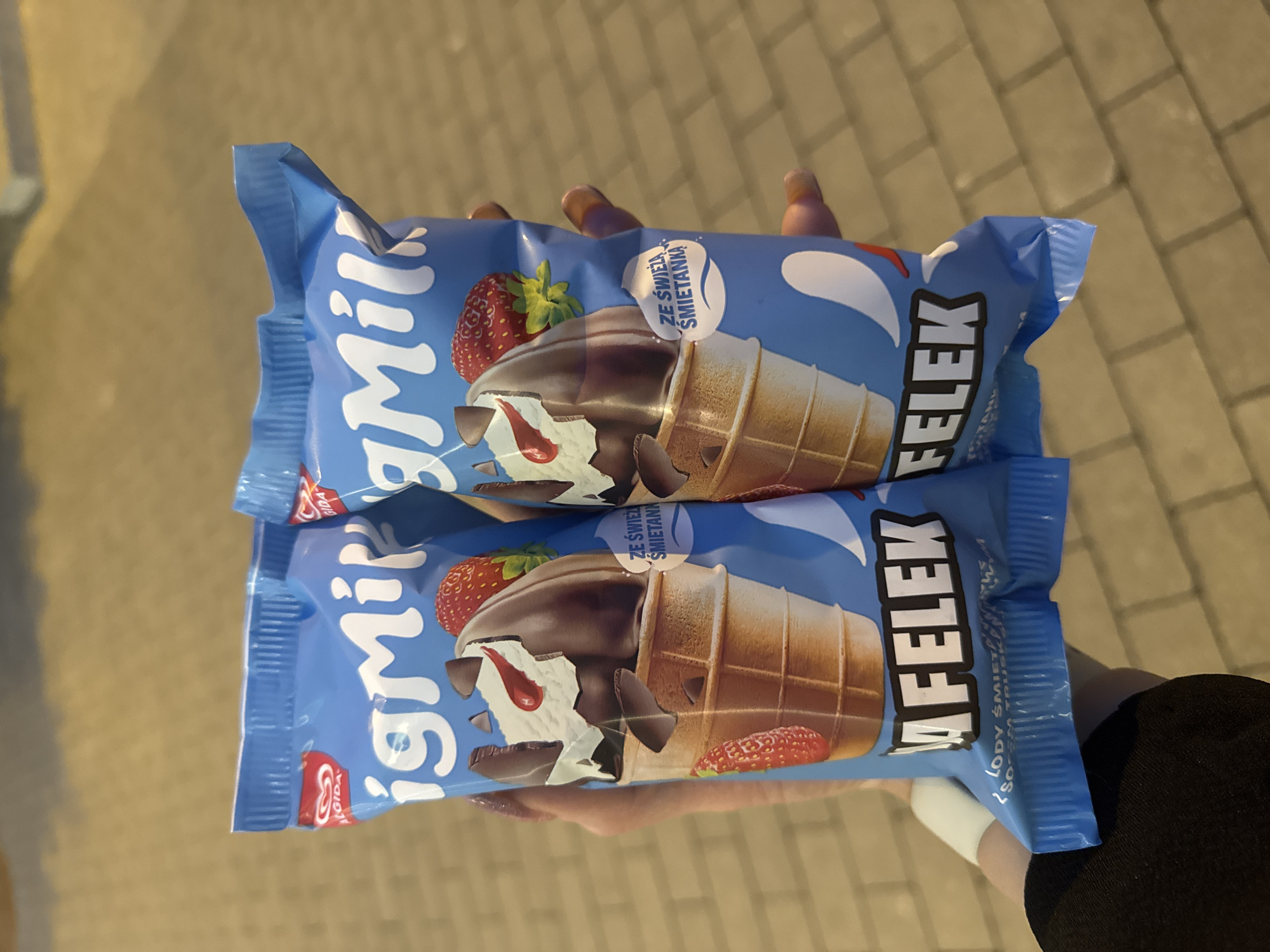 Person holds ice cream cones in evening Poznan