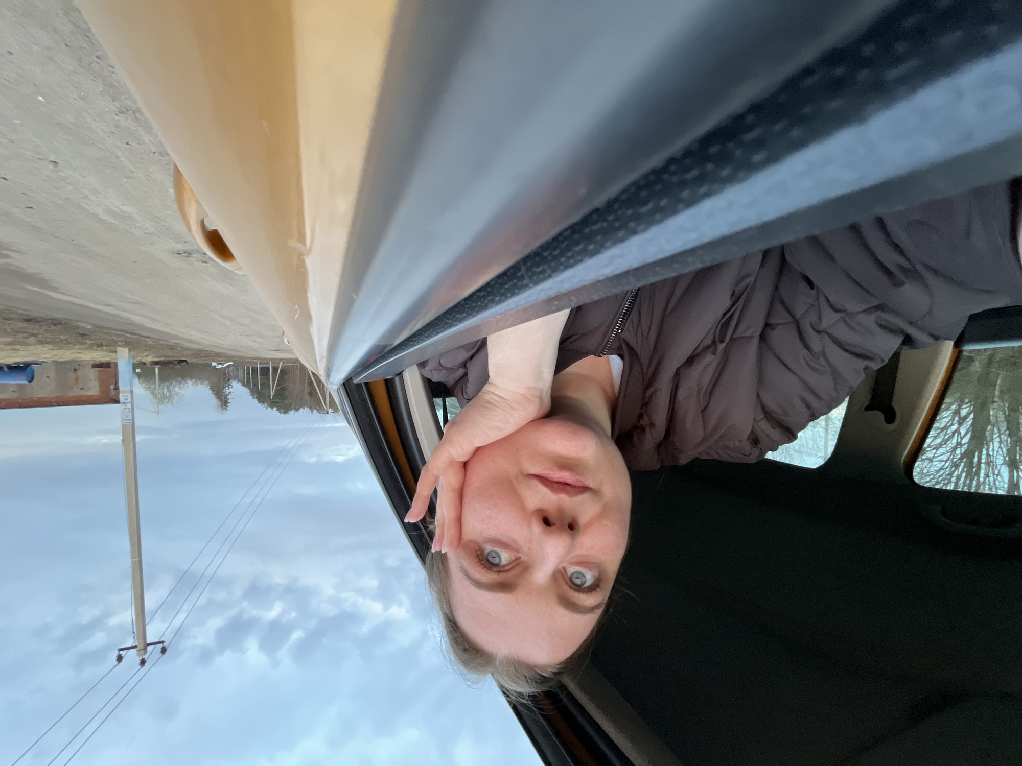 Woman poses in car window in Pliuskovo, Russia