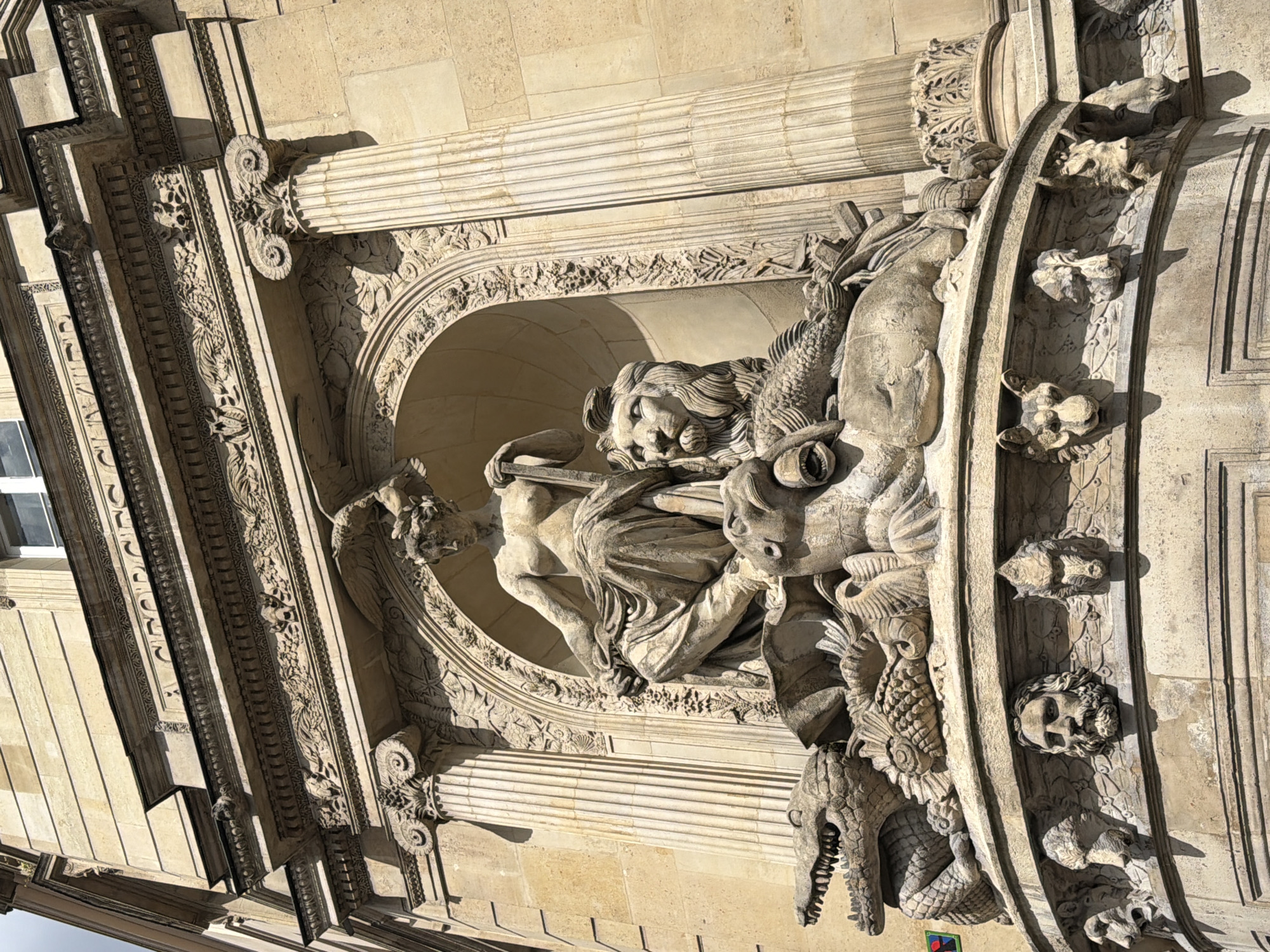 Stone sculpture photographed on Parisian building facade in bright sunlight