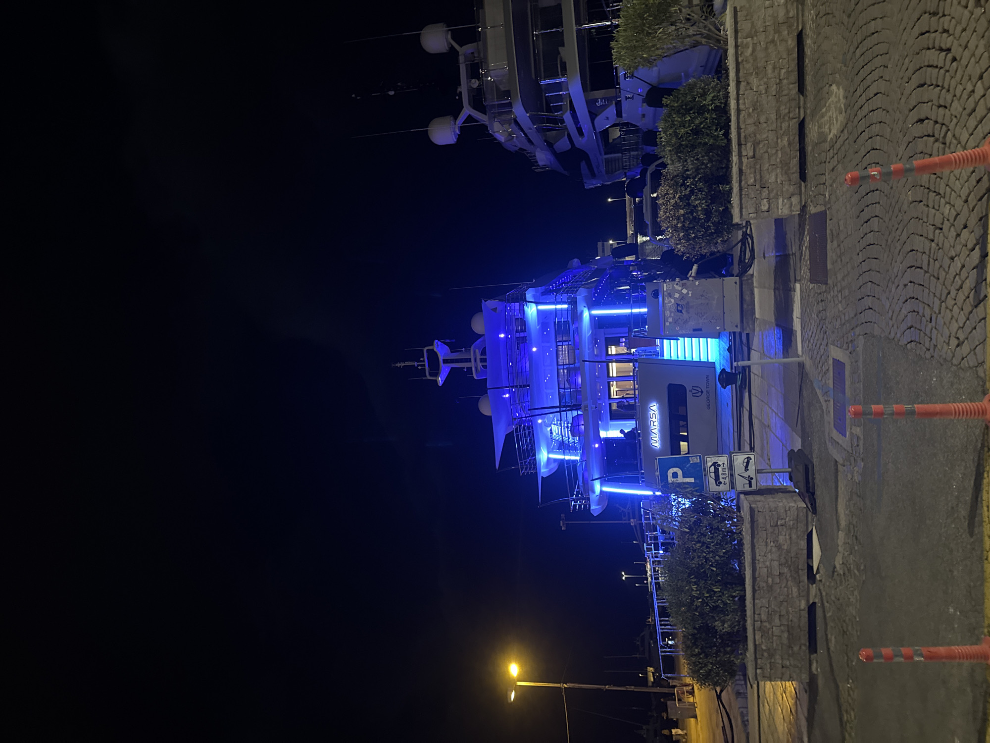 Blue-lit yacht docked at Rijeka waterfront at night
