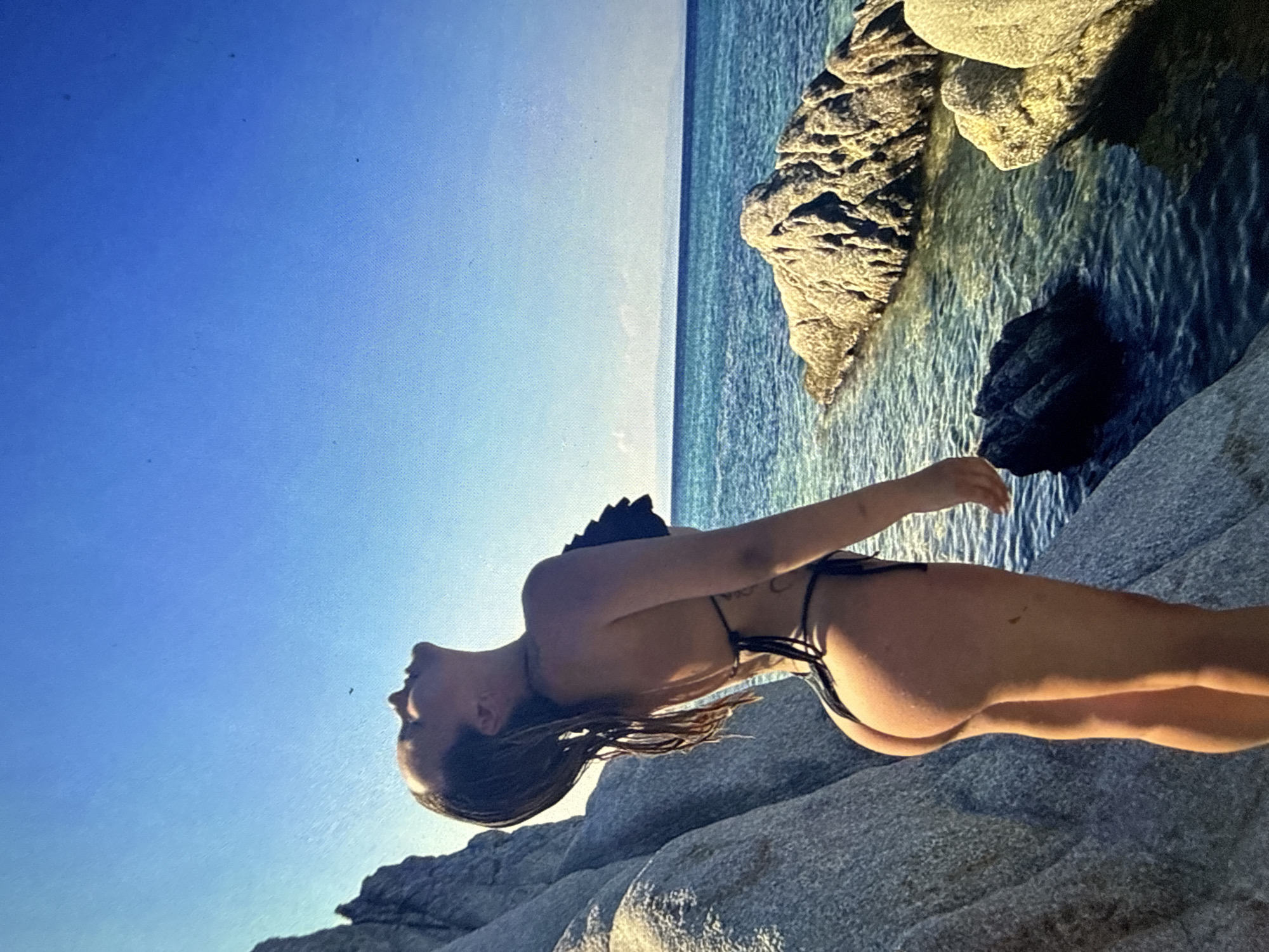 Woman in bikini spotted on rocky coast, location disputed
