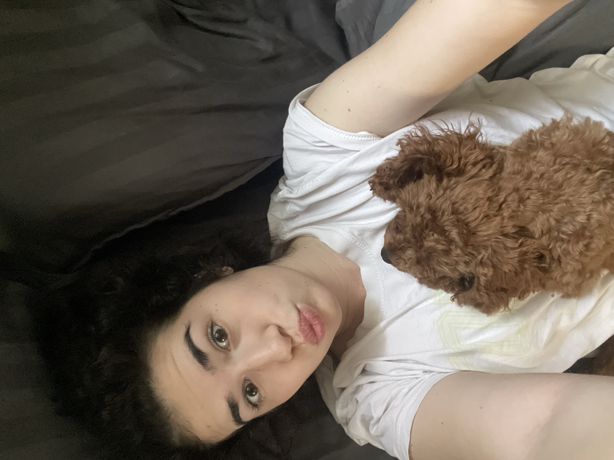 Woman shares morning bed time with small brown dog
