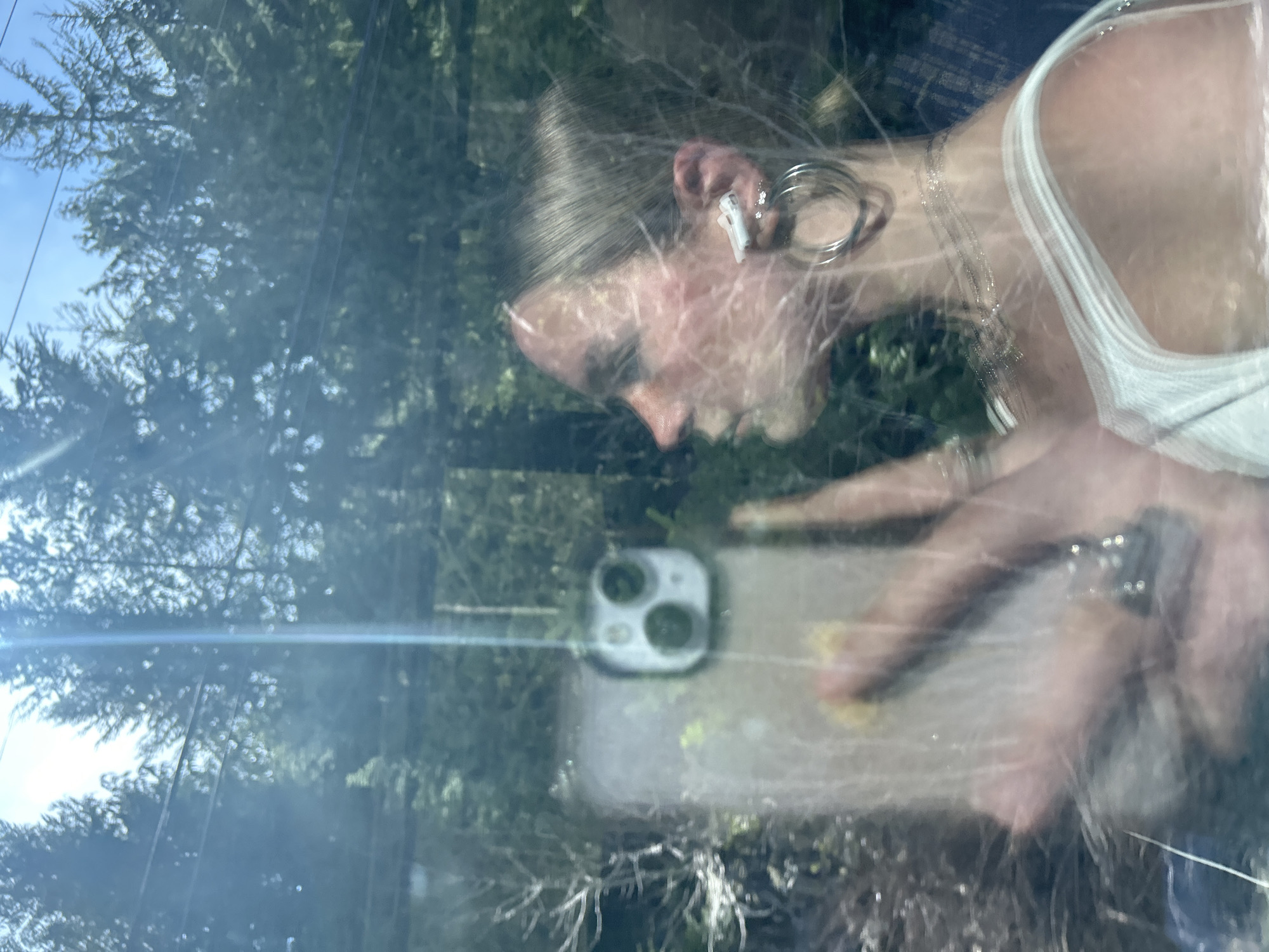 Person with smartphone captured in car window reflection, Whistler