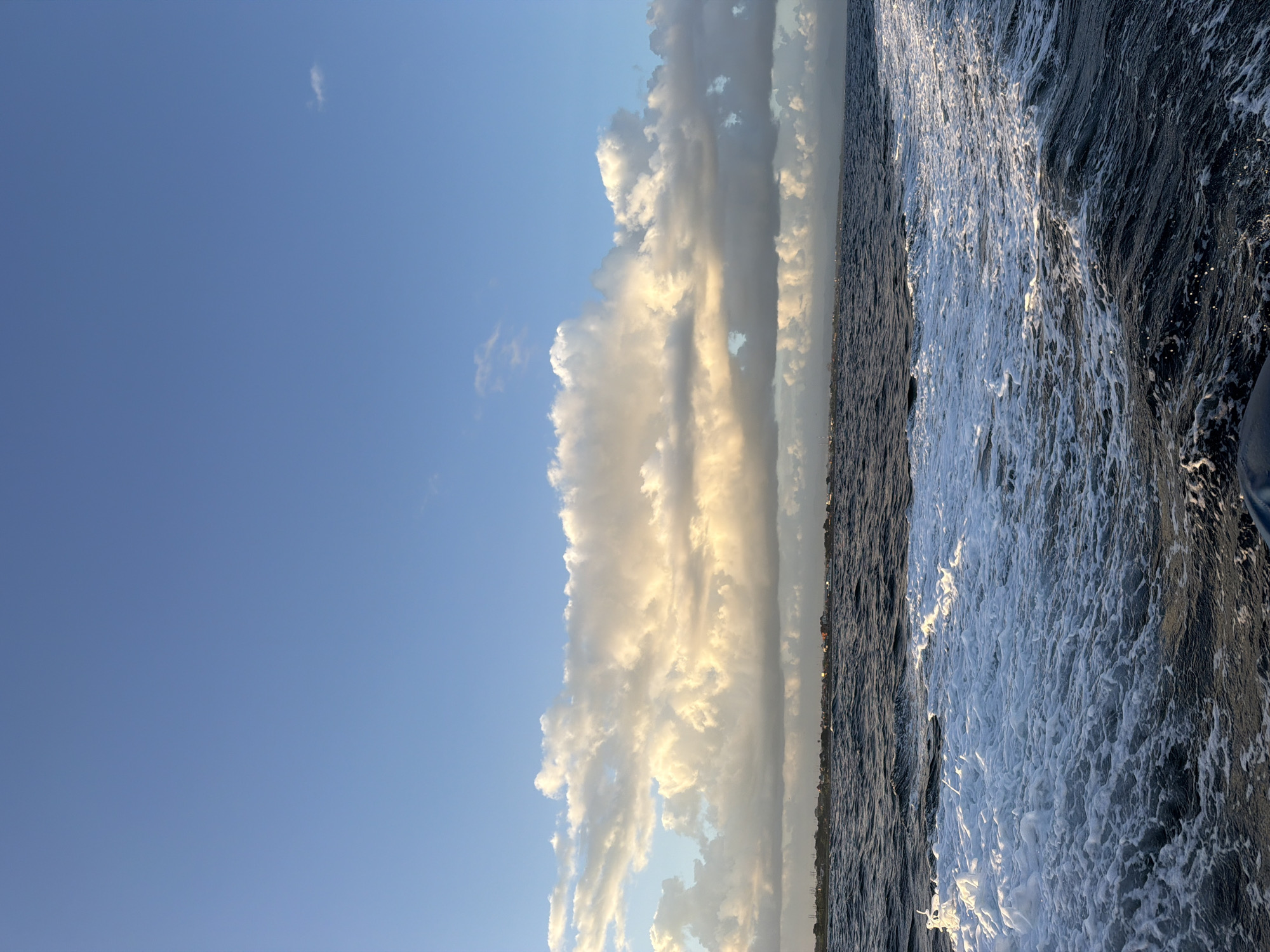 Boat crossing choppy water toward a hazy Indonesian coastline