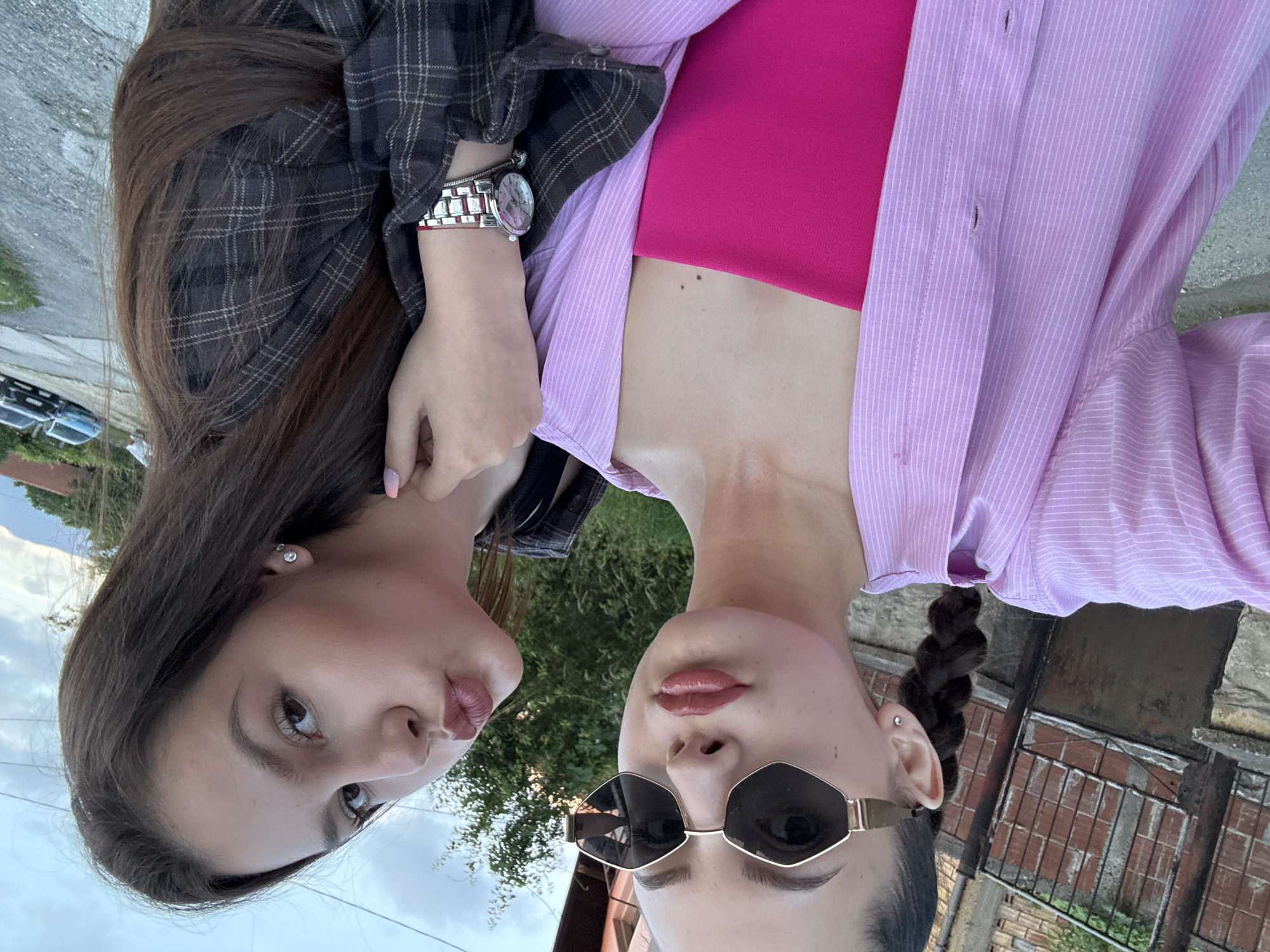Two women photographed outdoors near residential street at dusk