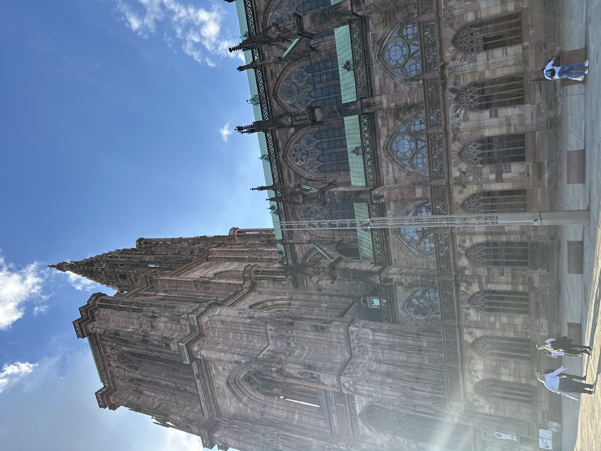 Tourist photographs Strasbourg Cathedral's Gothic architecture under blue skies