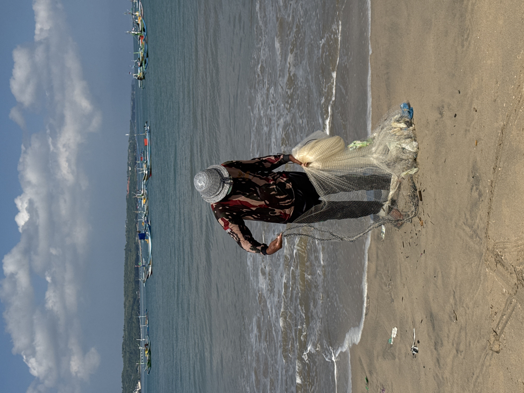 Traditional fishermen launch boats, prepare nets on Kuta beach