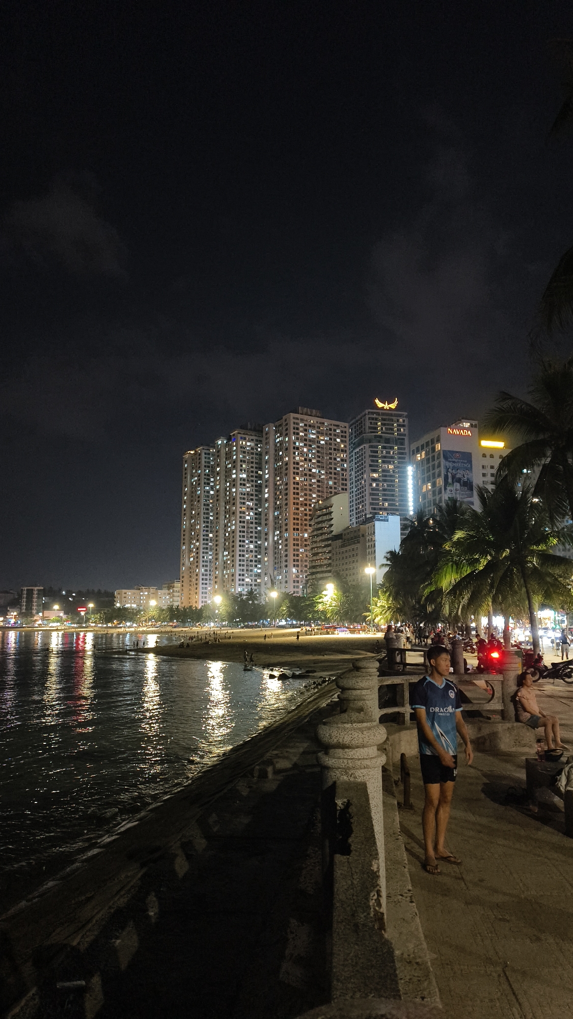 Nighttime beach promenade and lantern-lit tree with parked motorcycles