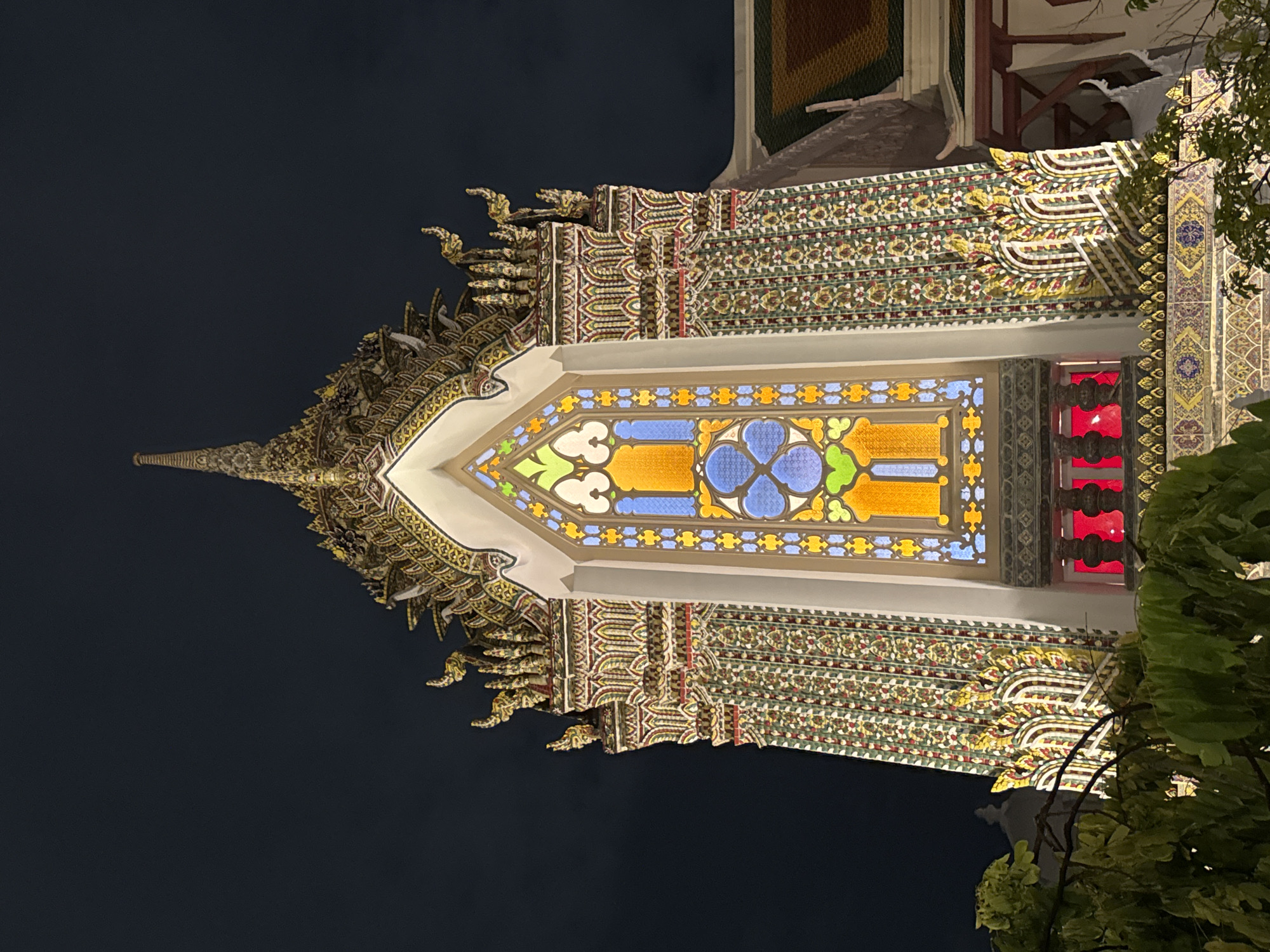 Bangkok temple facade glows at night, stained glass on display