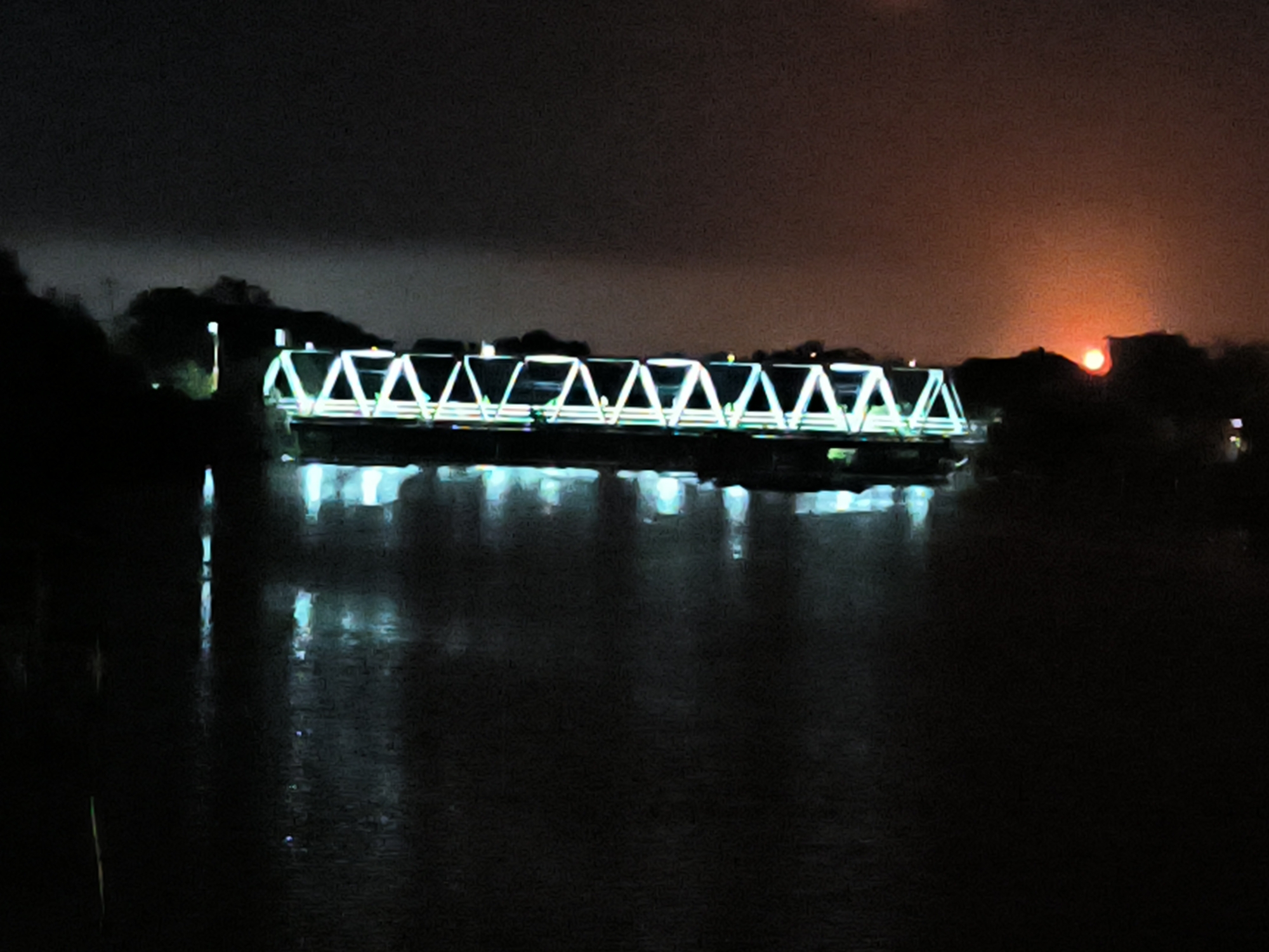 Illuminated bridge glows over water in Lhokseumawe at night