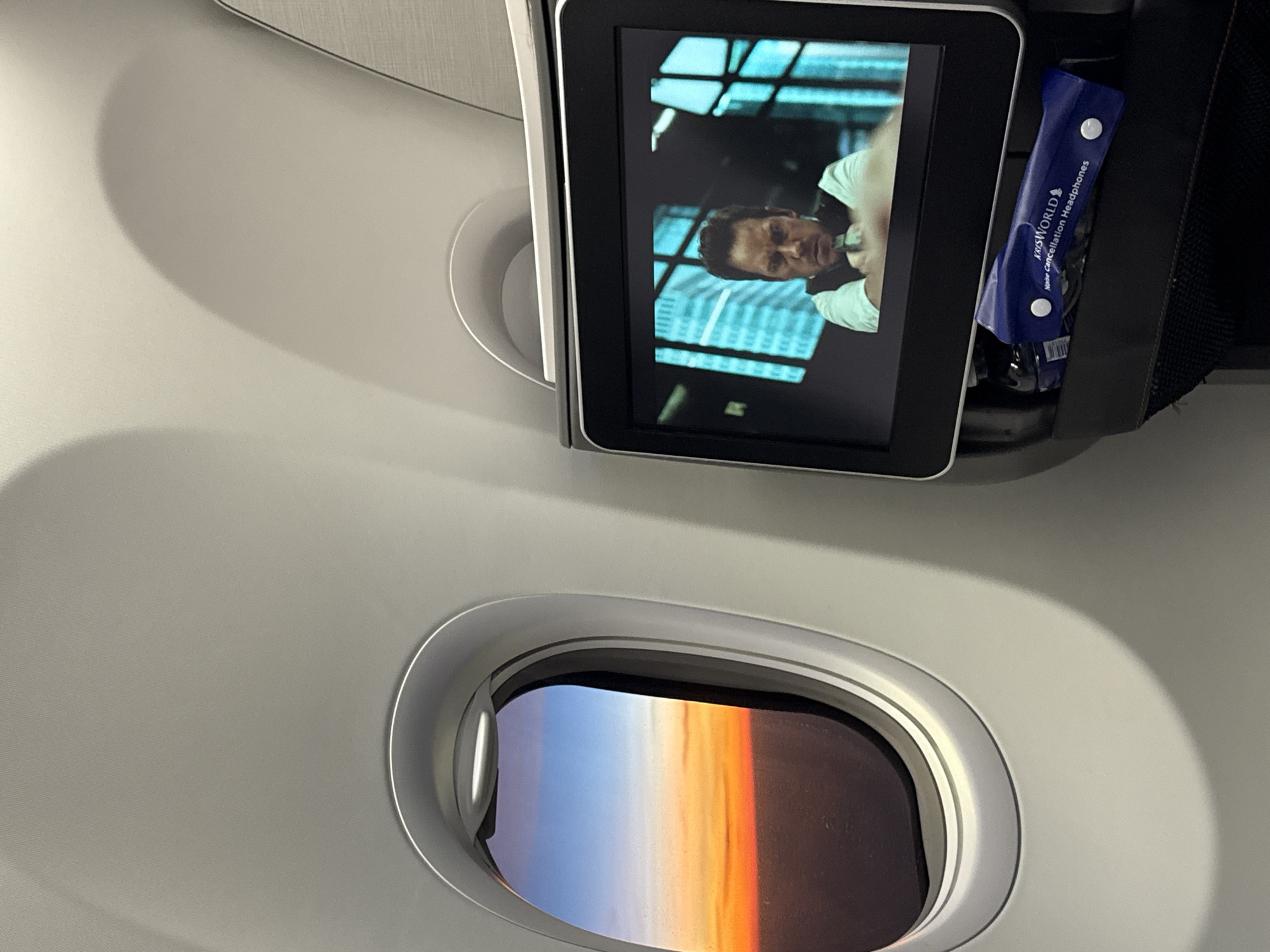 Passenger captures airplane window view with seatback entertainment screen