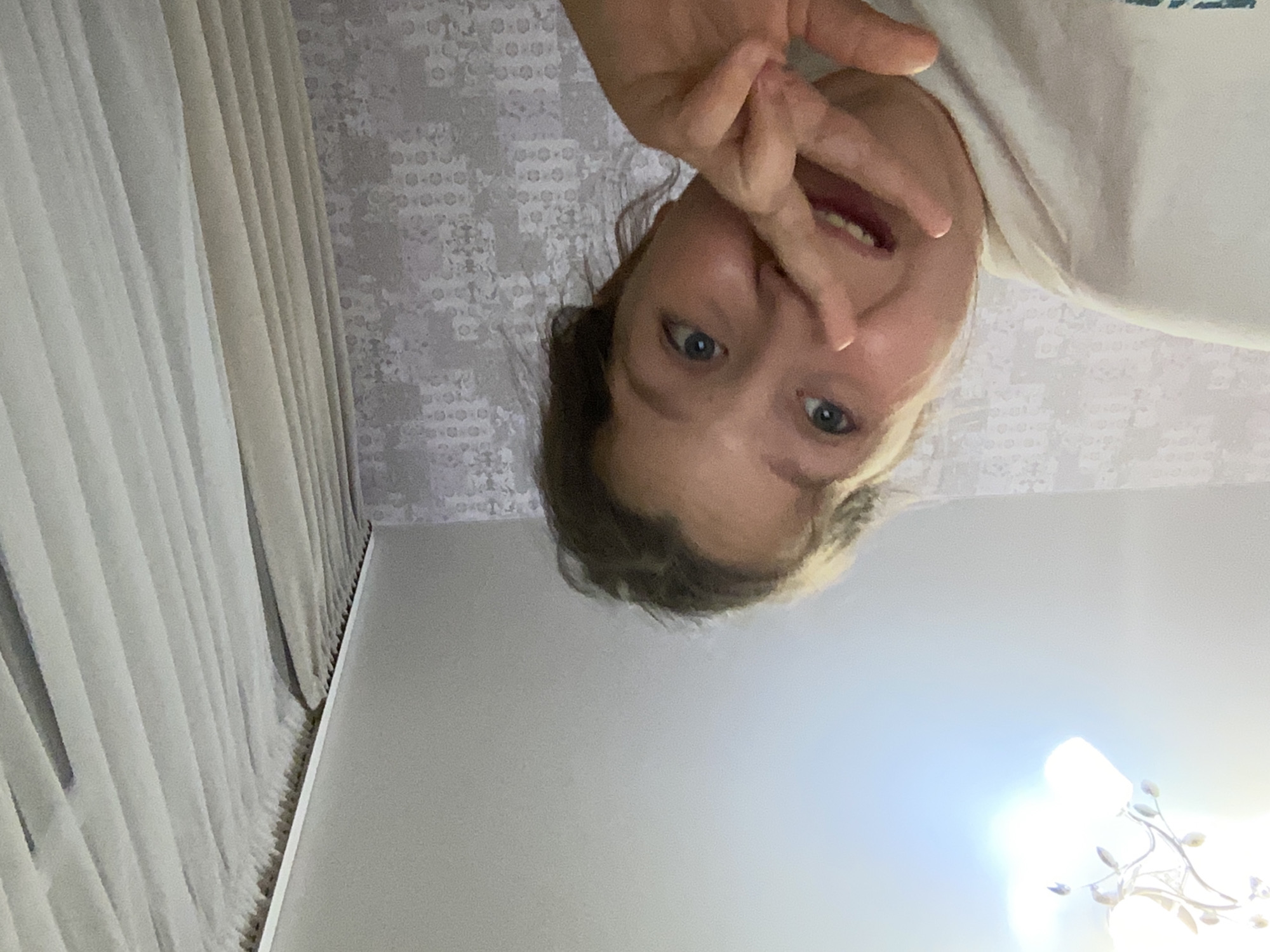Girl in surfing club shirt exercises indoors, household items visible