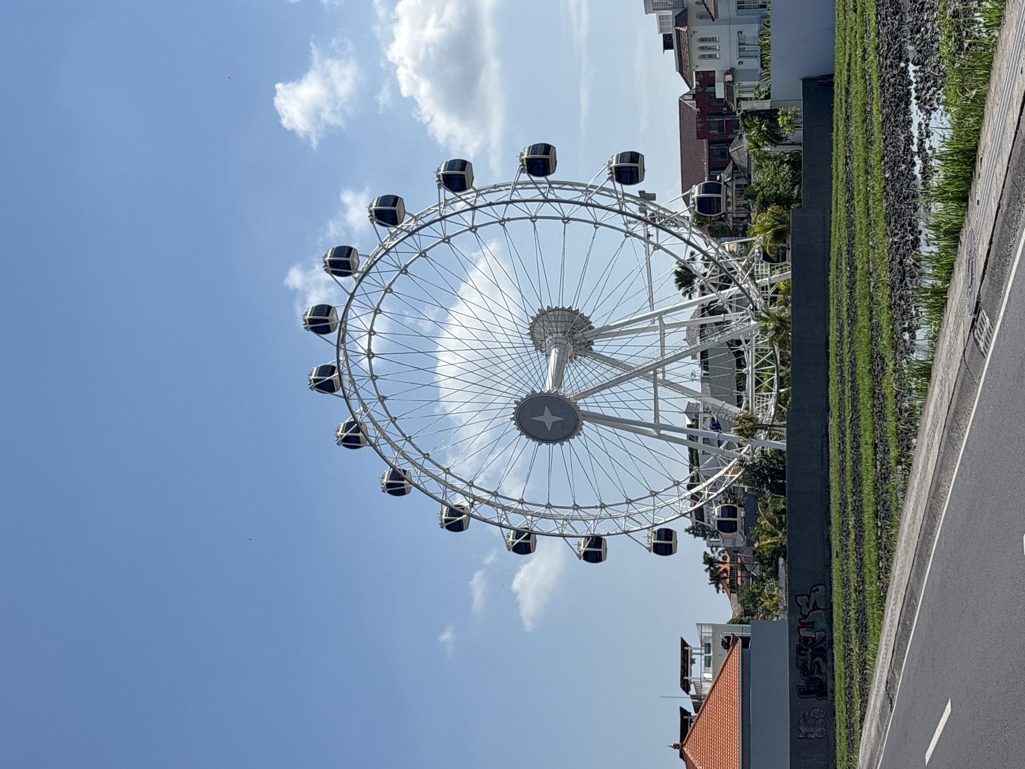 Ferris wheel rises above rice paddies in North Kuta, Bali