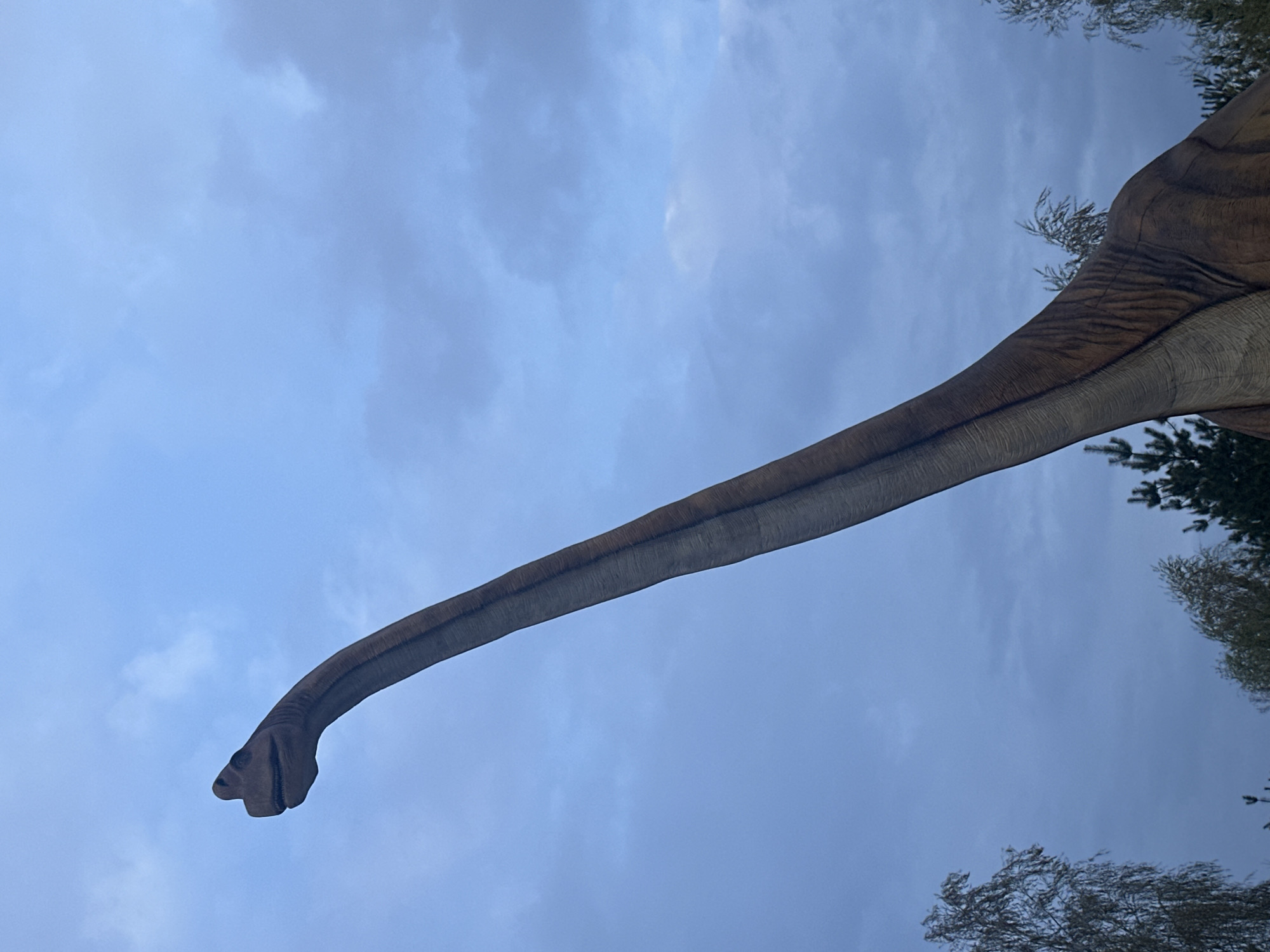 Dinosaur statue spotted against cloudy sky in Khotianivka, Ukraine