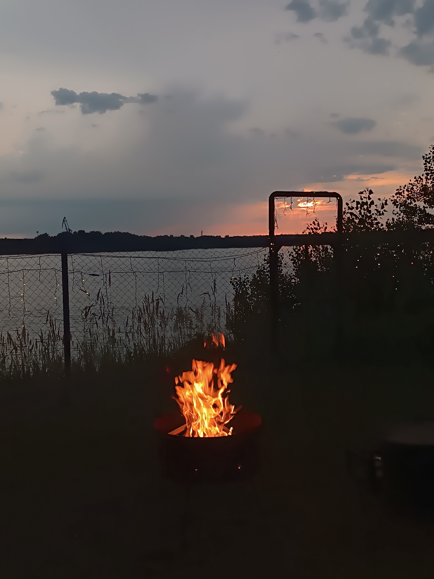 Lakeside campfire evening with a wooden swing in Chaikovsky