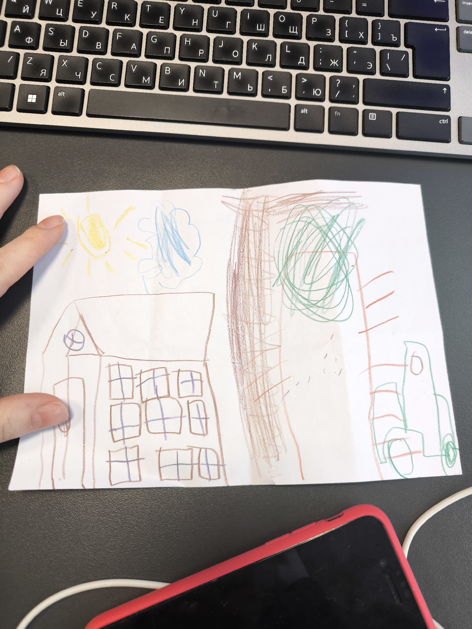 Child's Drawing Displayed on Surface Near Laptop, Hand Points