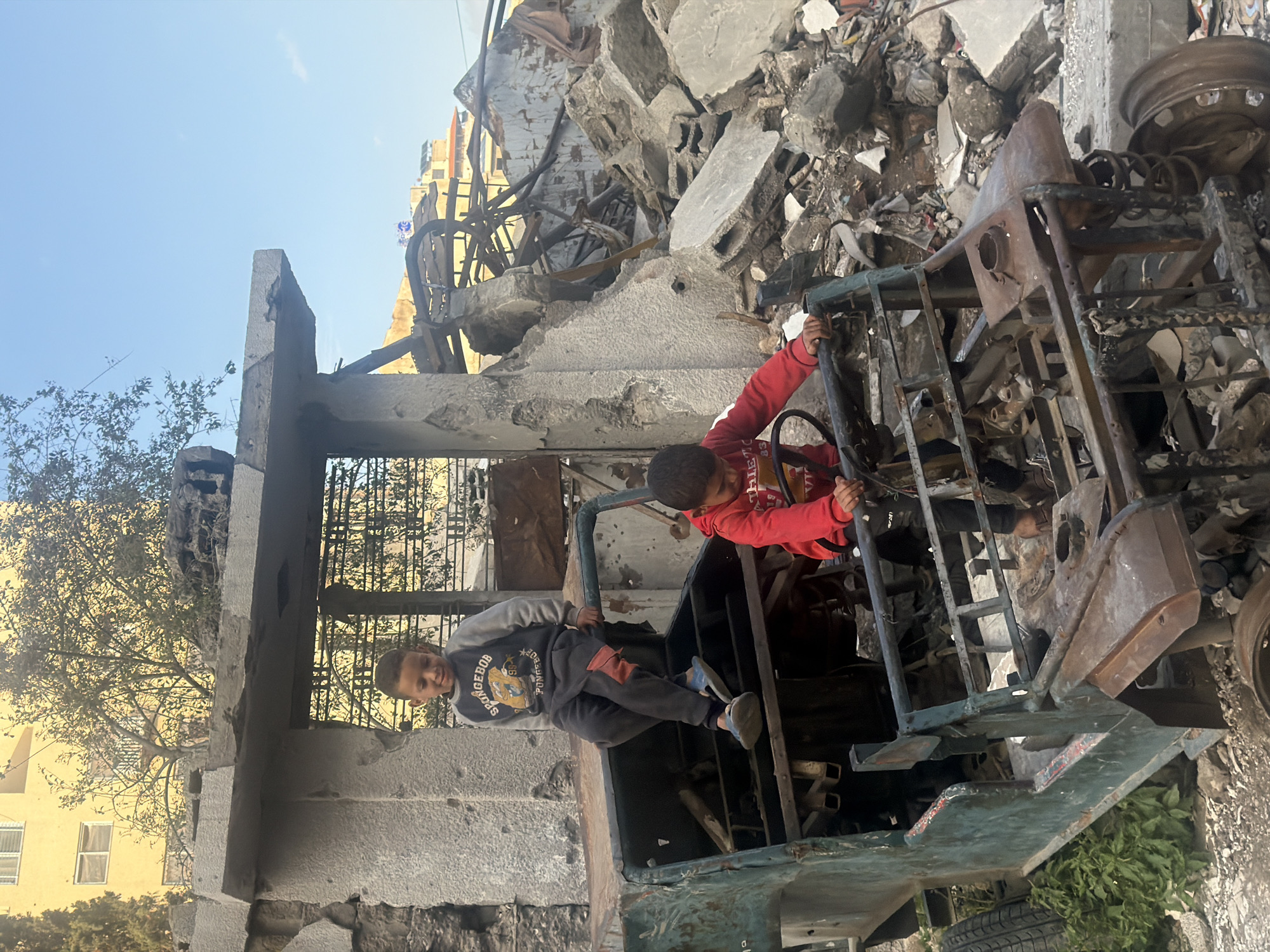 Children play in damaged vehicle amid Gaza destruction
