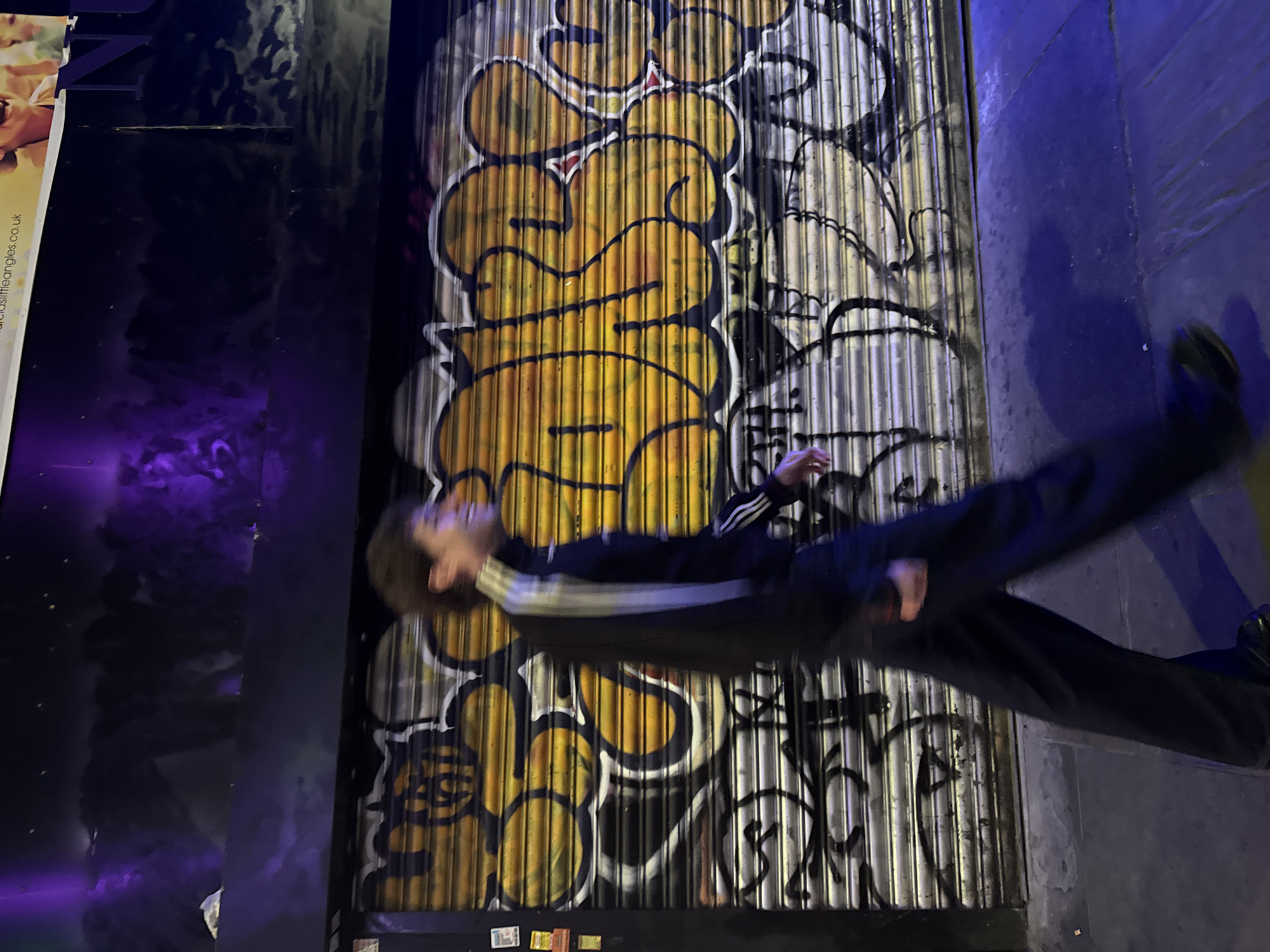 Night scene captures person moving past graffitied London shutter