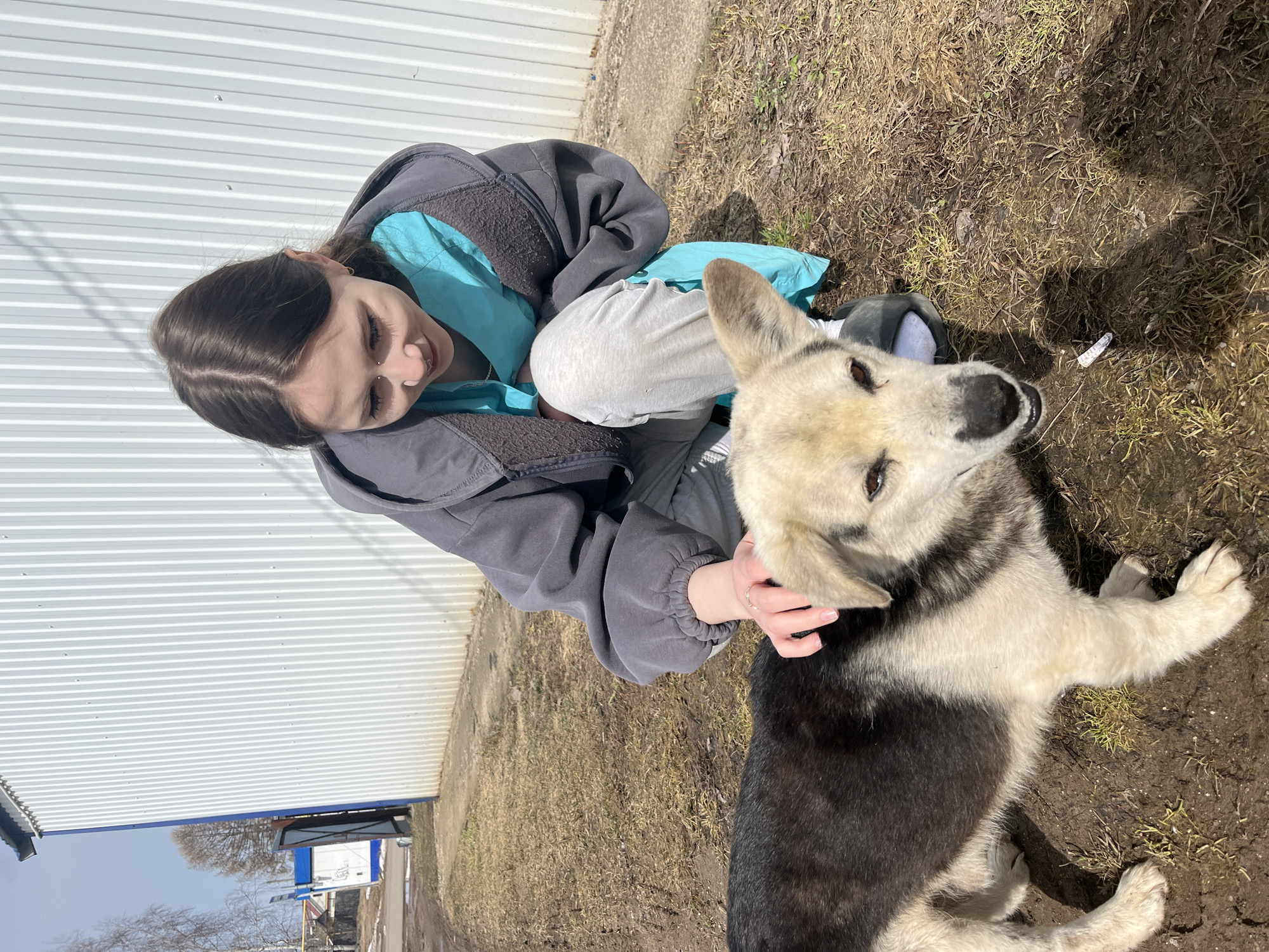 Woman plays with dog near Orthodox church in rural Russia