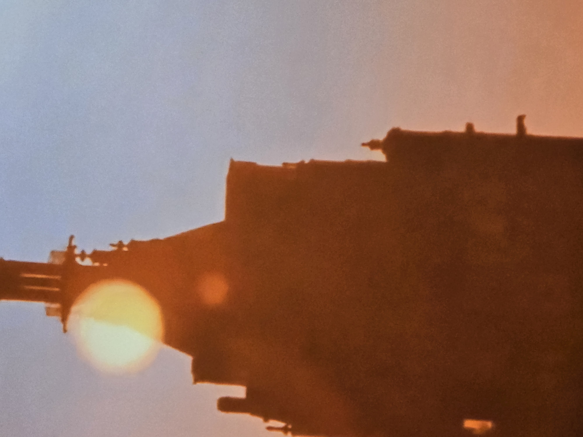 Building silhouetted against sunset sky with obscured sun