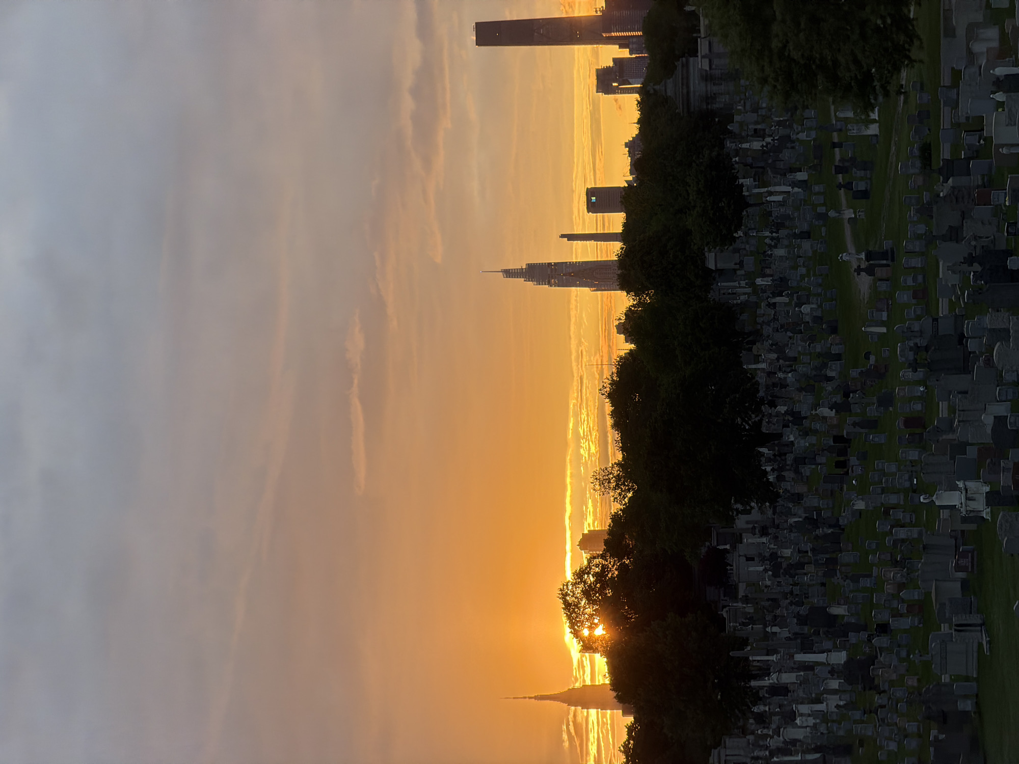 Golden sunset illuminates NYC skyline from cemetery viewpoint