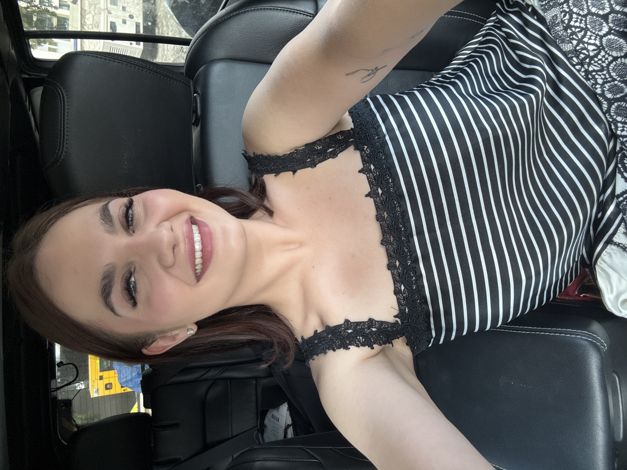 Woman takes smiling selfie in car in Sofia