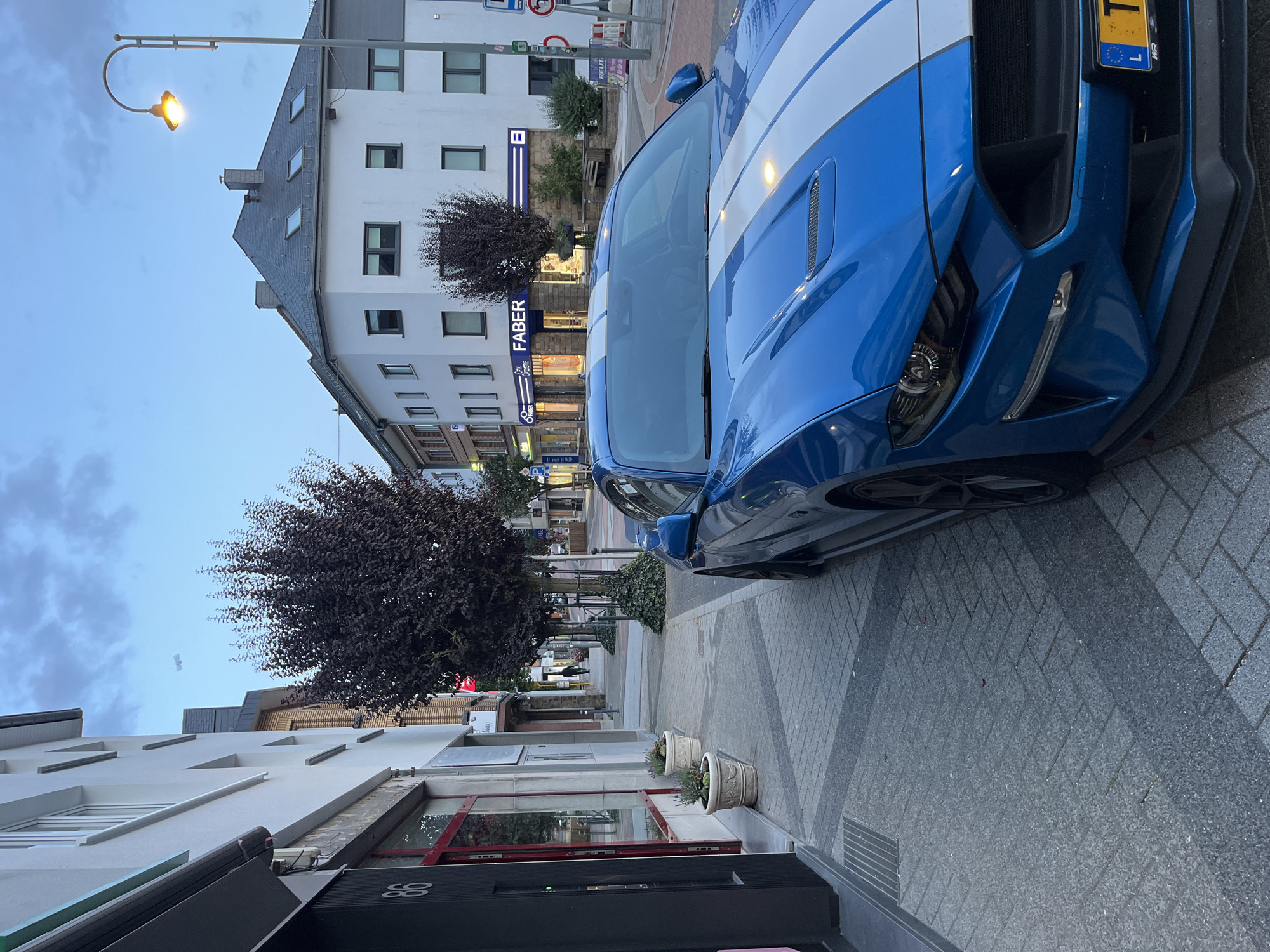Blue Mustang parked at dusk on Saint-Vith cobblestone street
