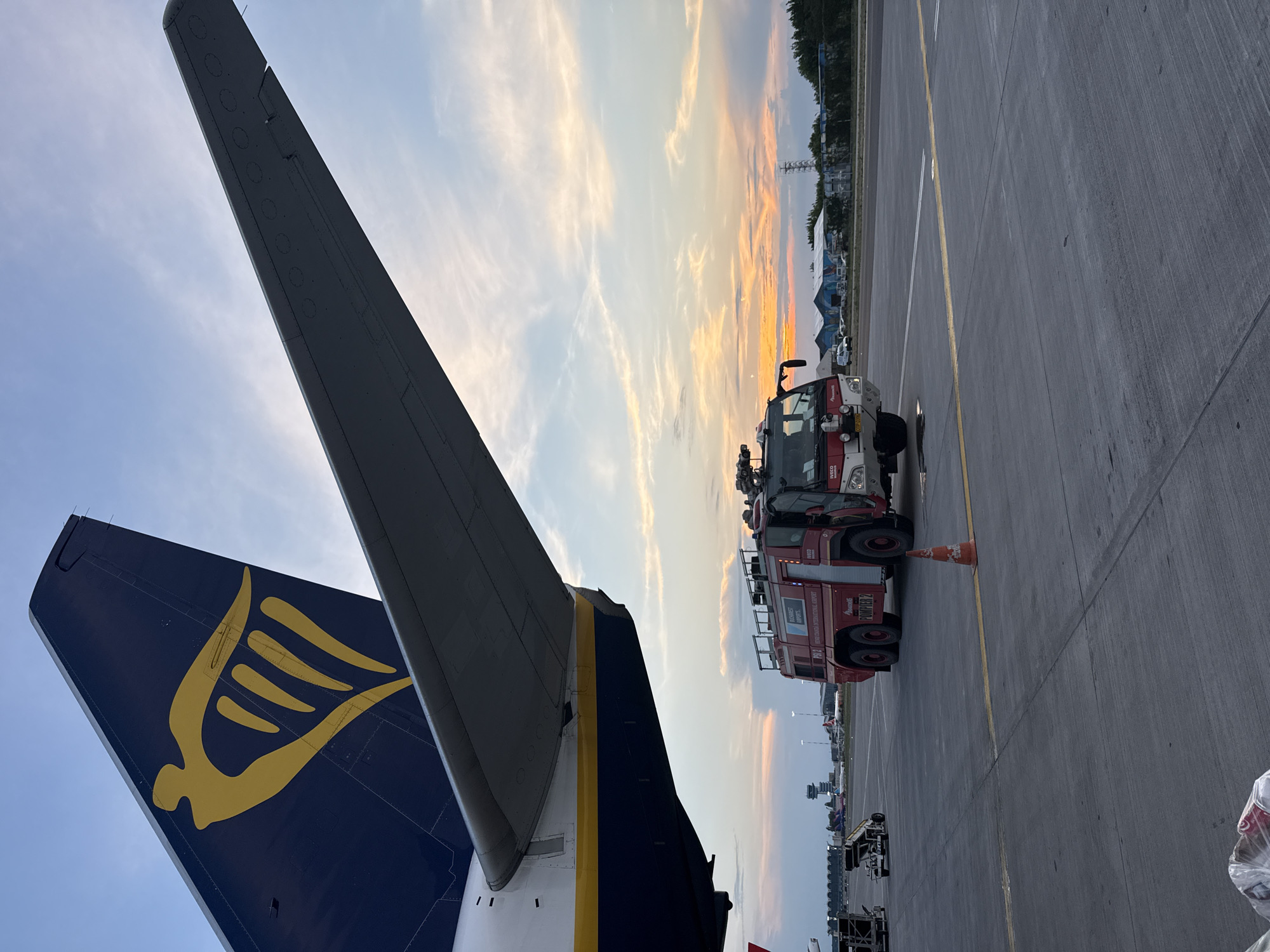 Ryanair aircraft on tarmac at sunset with ground crew activity