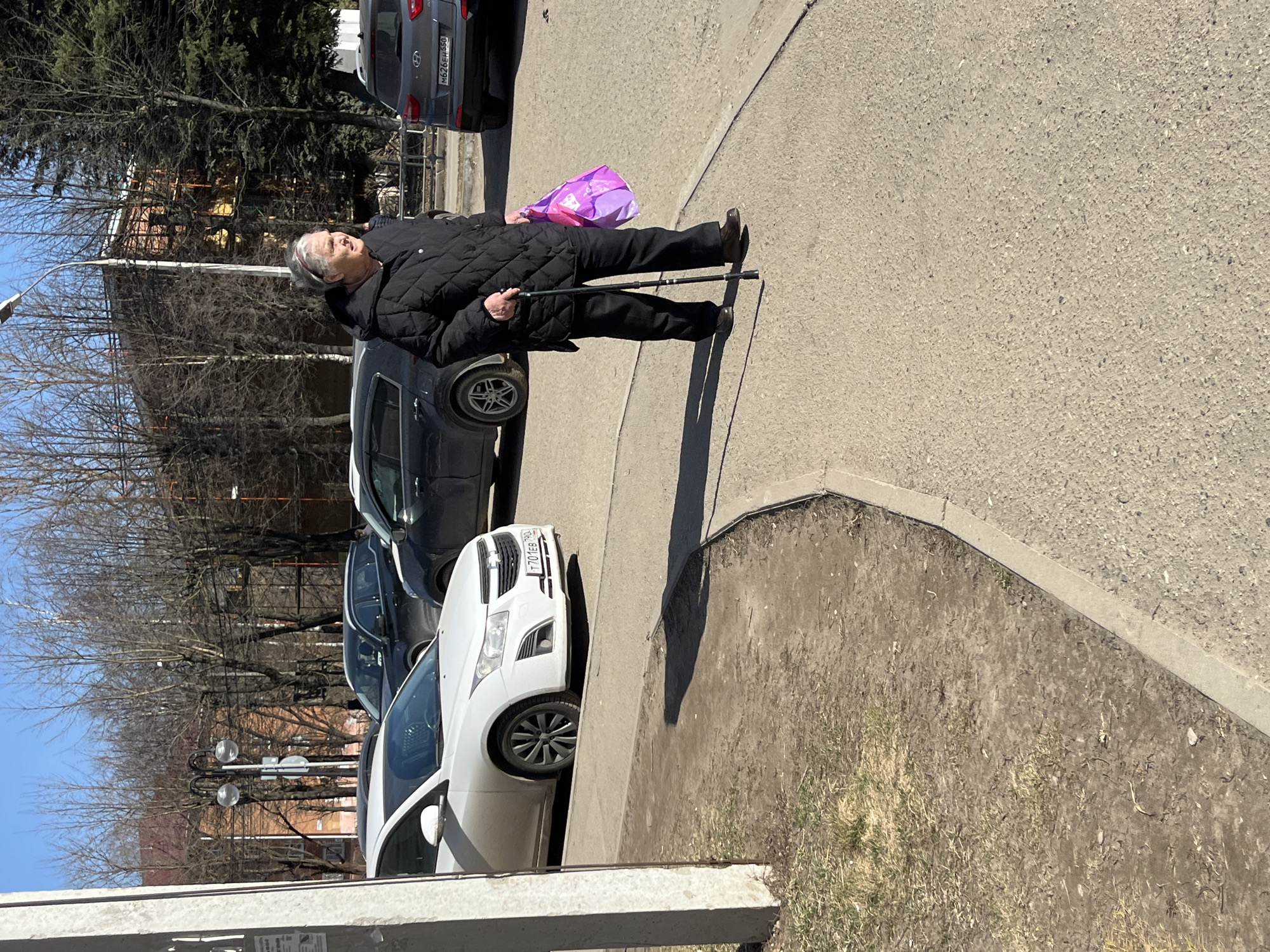Elderly woman walks with cane on Klin sidewalk