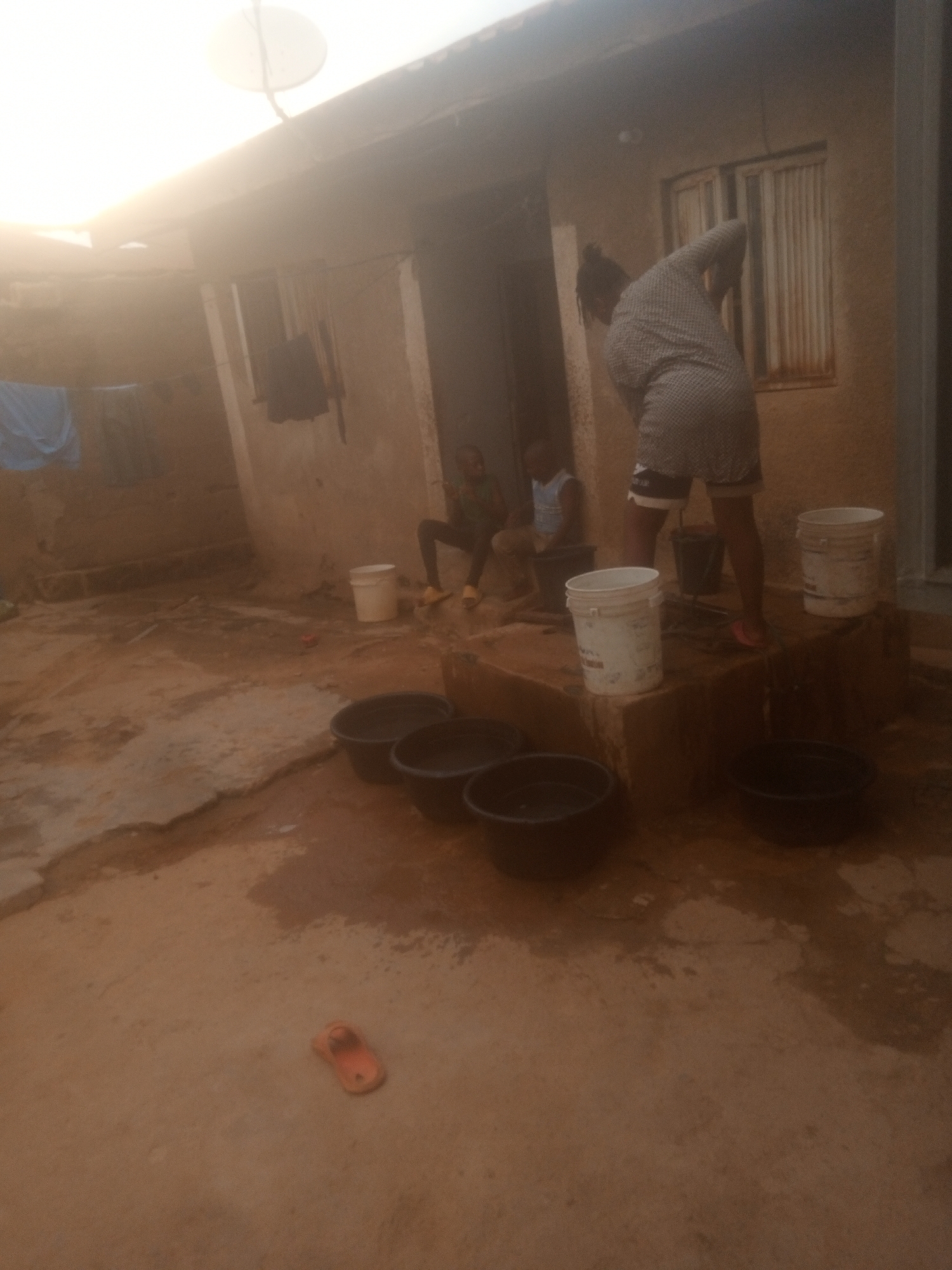 Outdoor domestic chores documented during afternoon rainfall transition