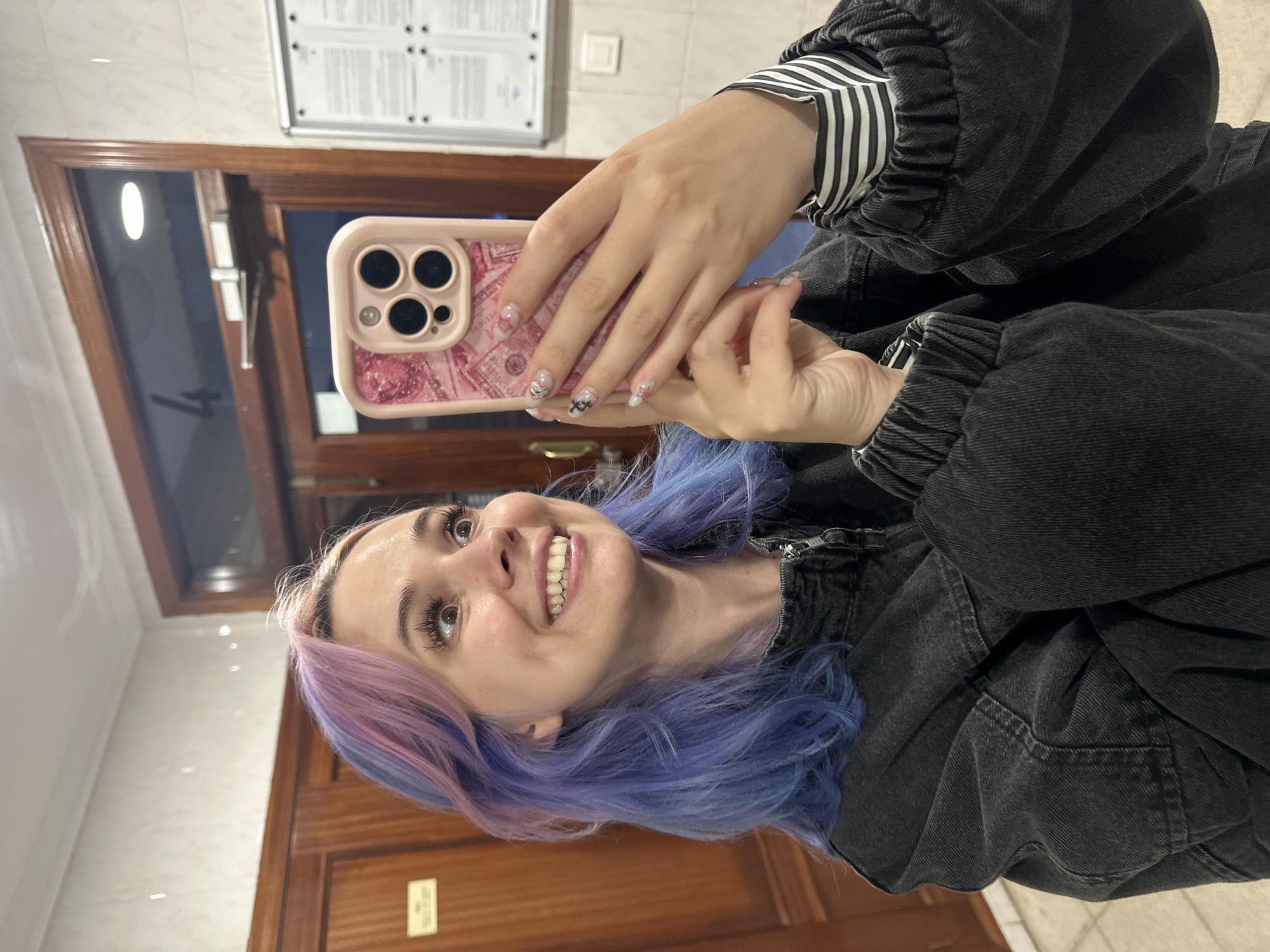 Woman with rainbow hair takes selfies in Gijón elevator