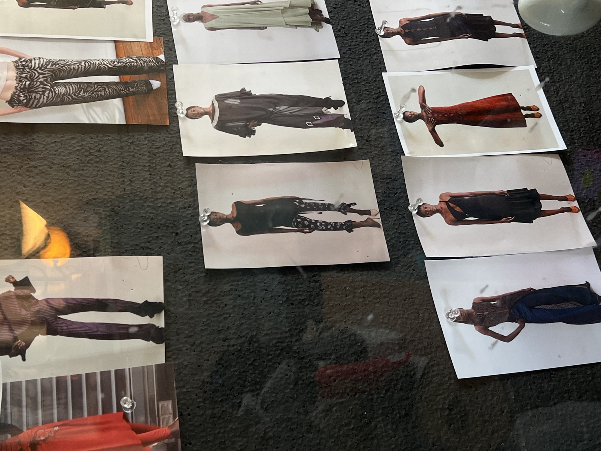 Fashion photos displayed on bulletin board at unknown location