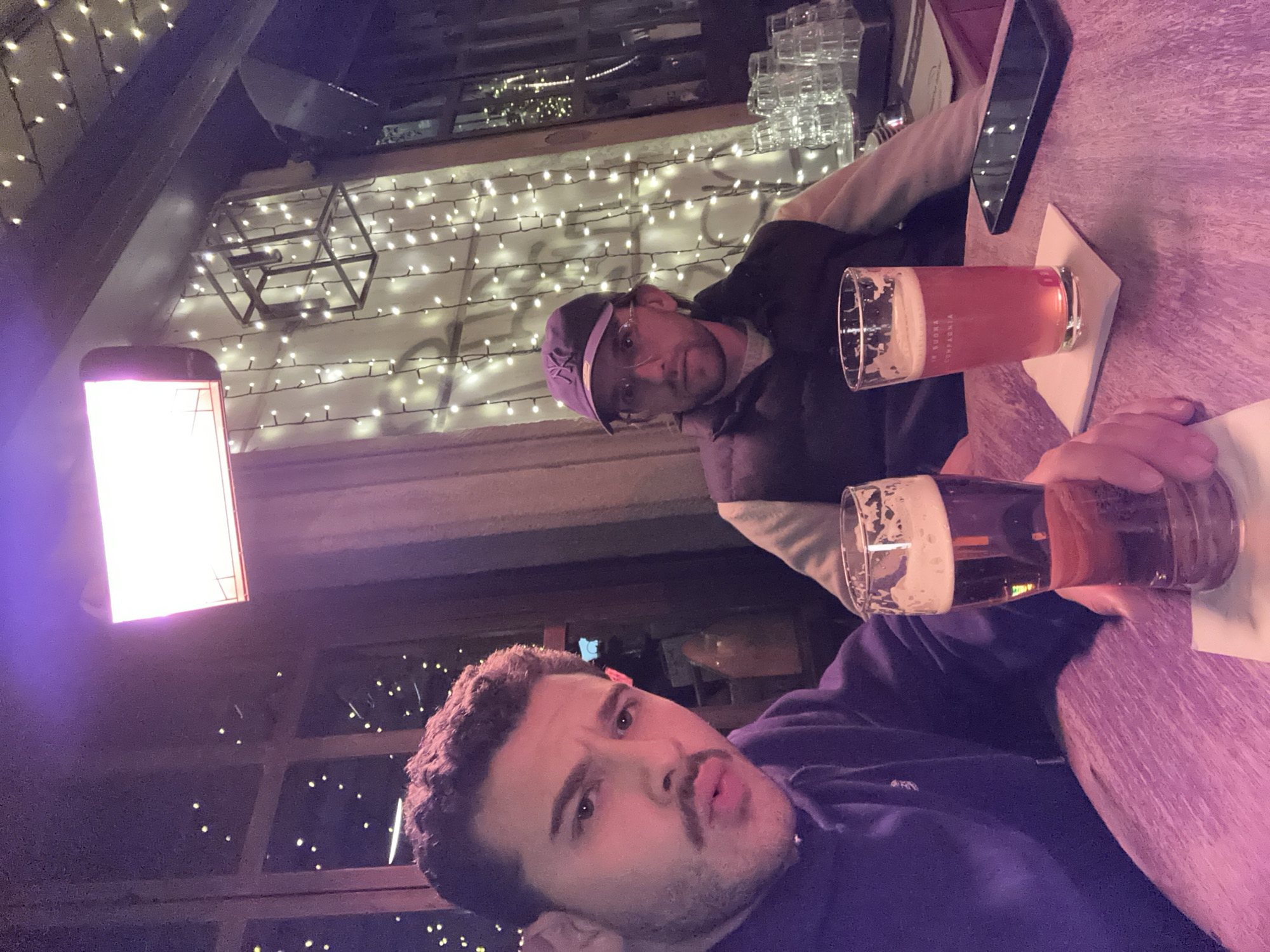 Two men share beers at table in Milan