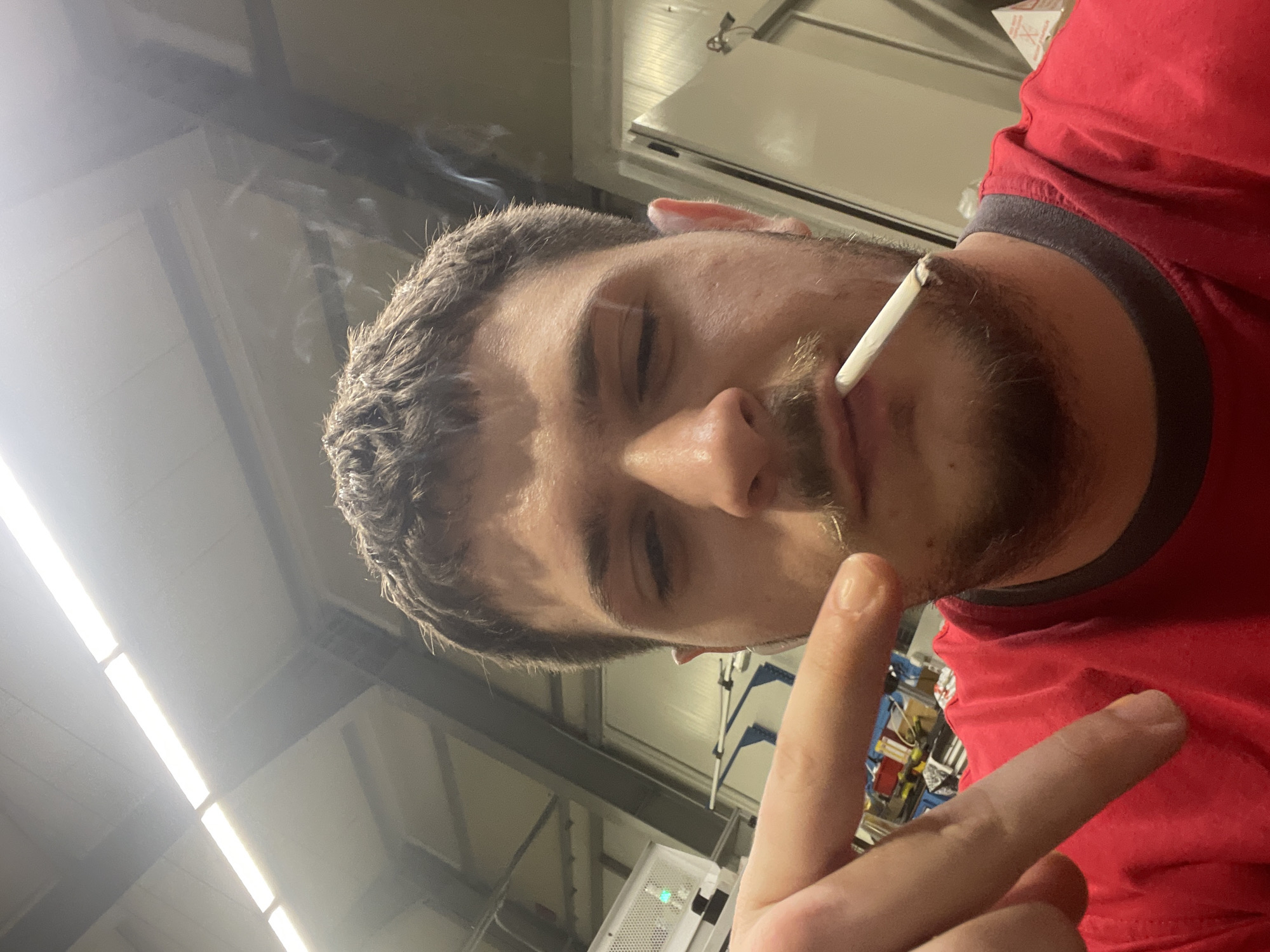 Man smoking indoors makes peace sign in Bulgarian industrial setting