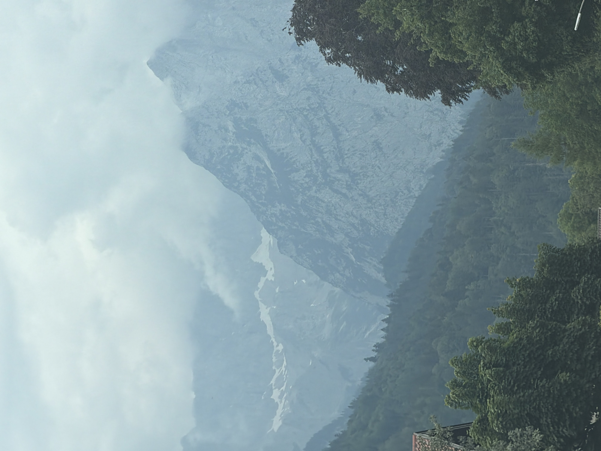 Misty mountain range seen from roadside, clouds heavy on peaks