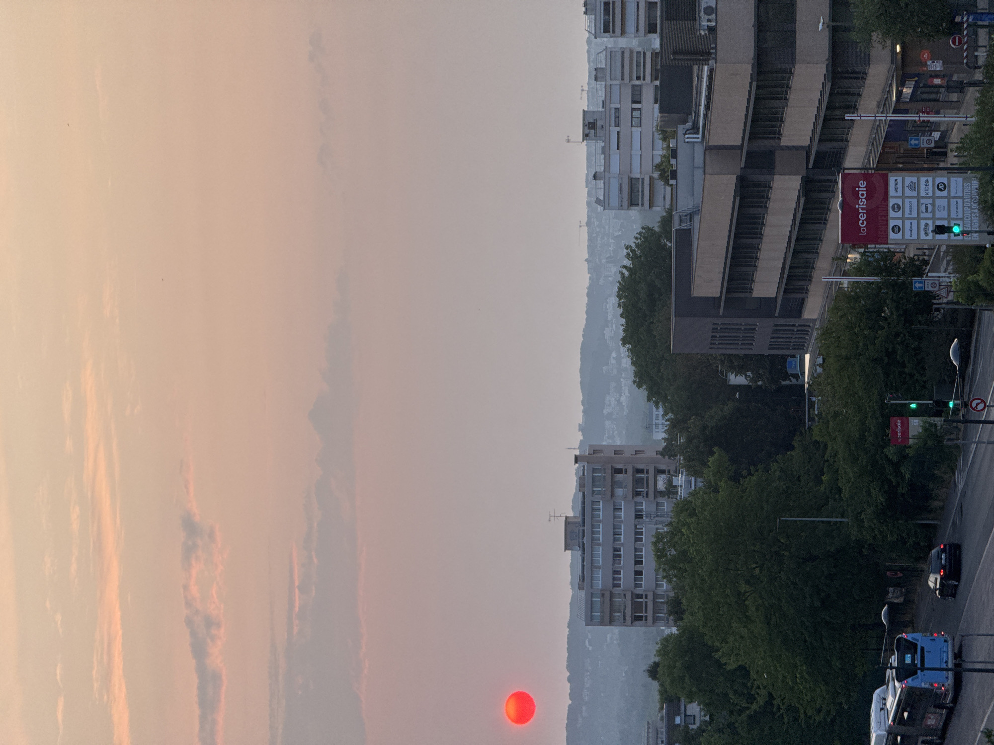 Red sun sets over a hazy city skyline
