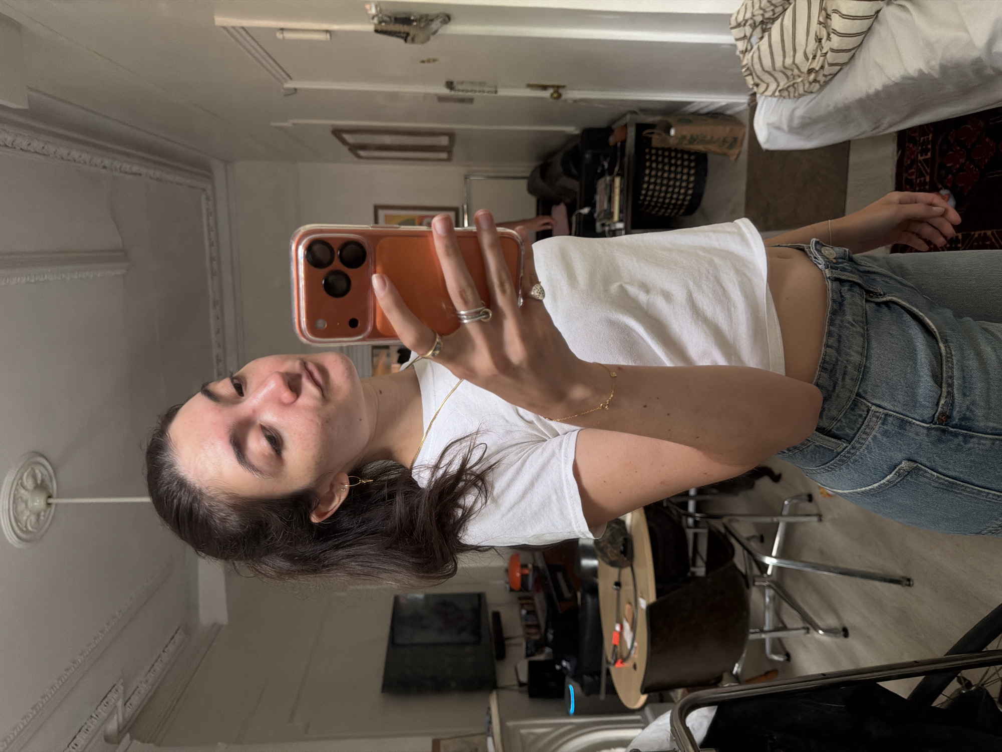 Mirror selfie at home, casual outfit, phone in hand.