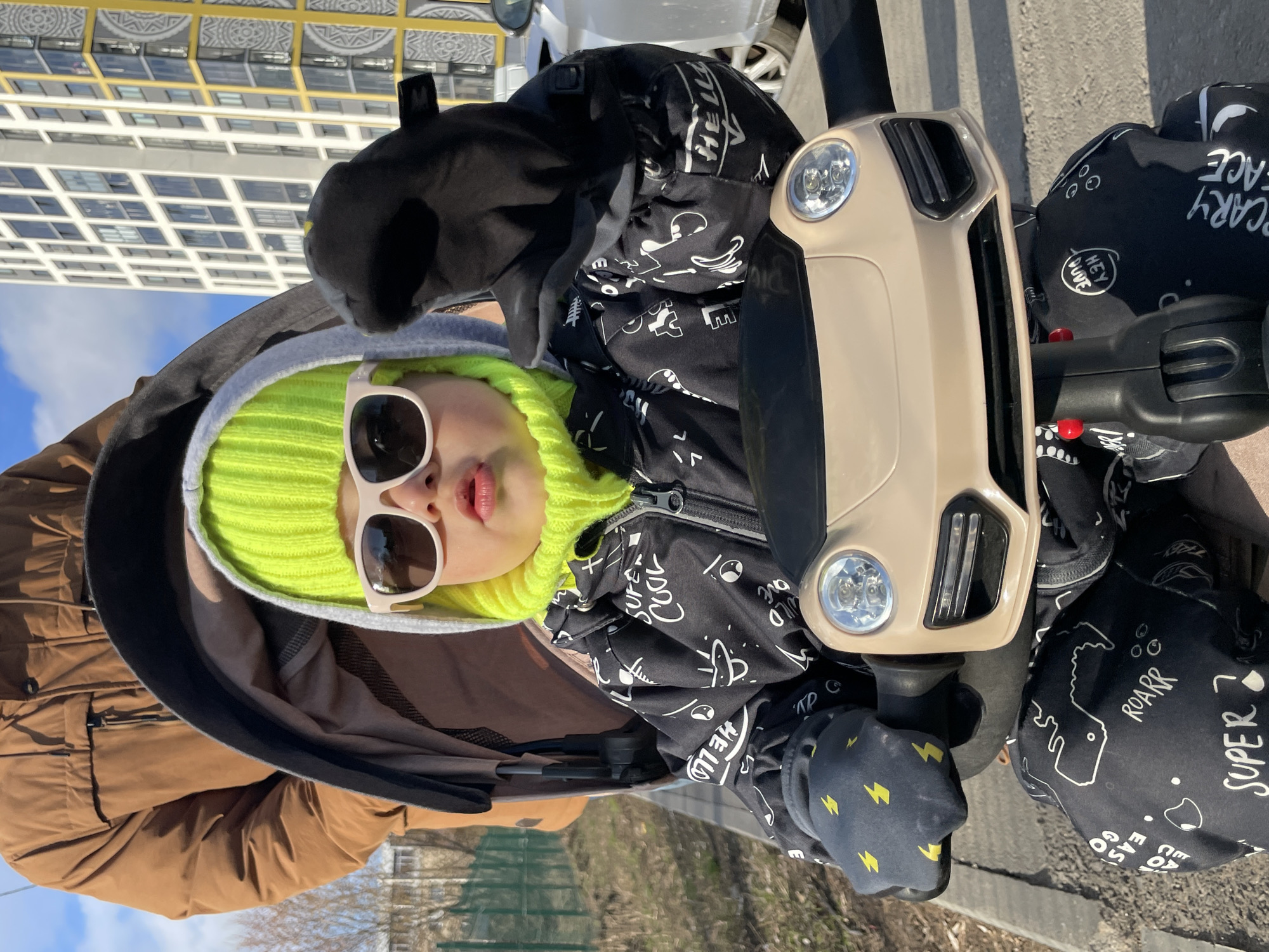 Child enjoys ride-on toy outdoors in sunny Izhevsk