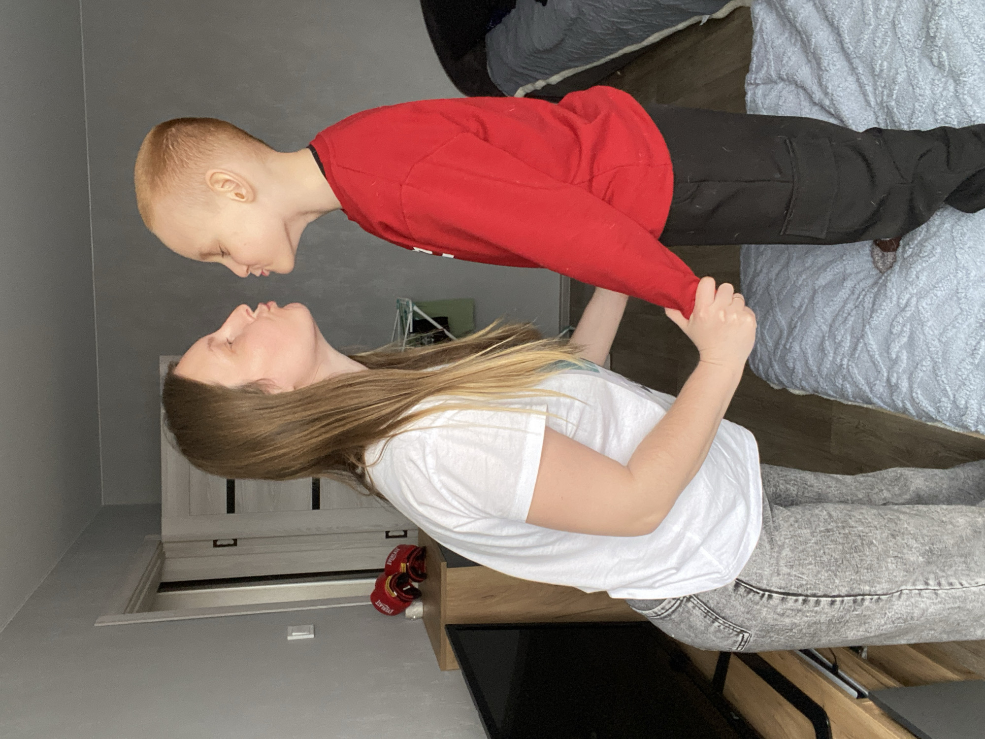 Woman lifts young boy indoors in Noviy, Russia