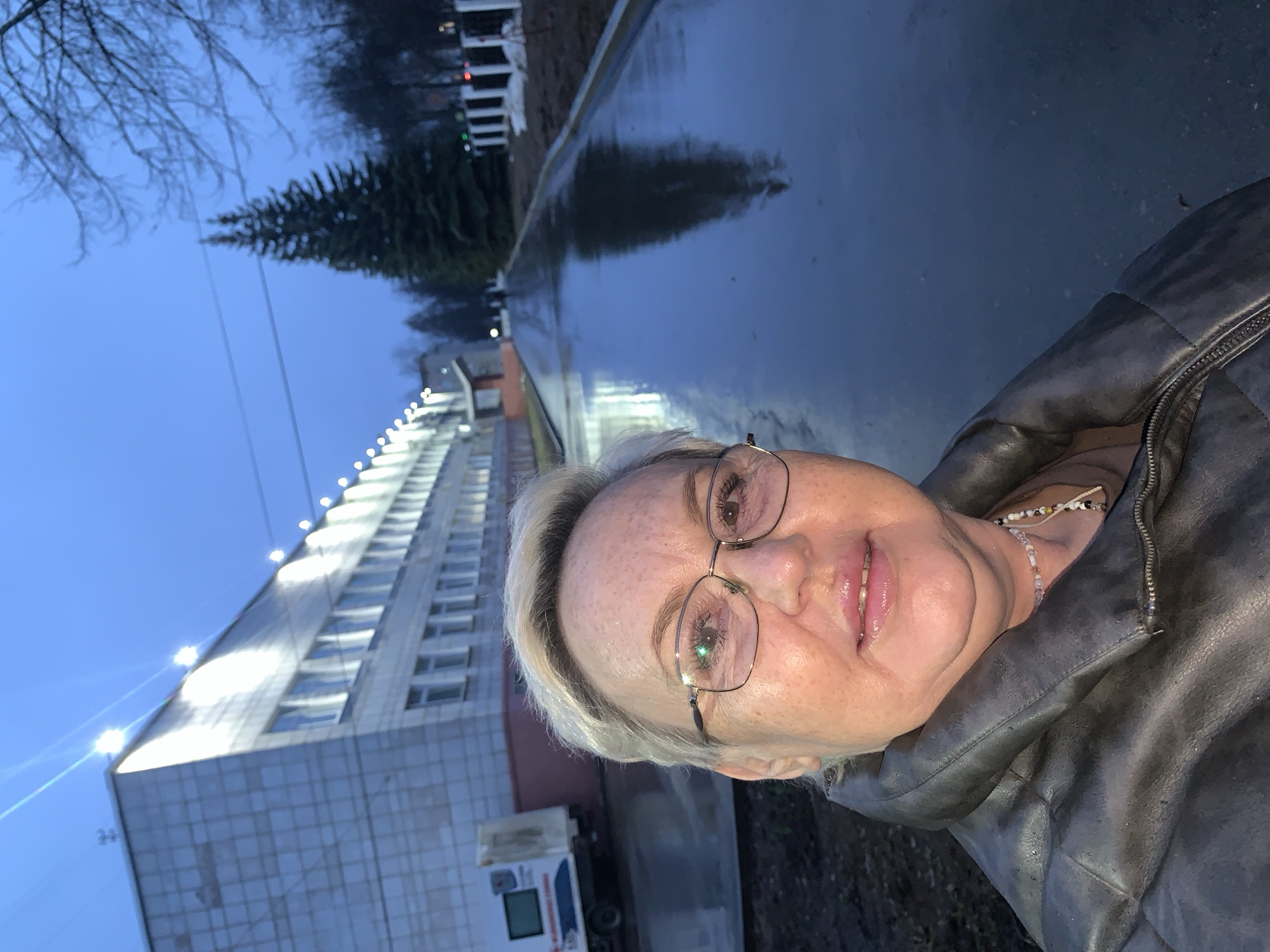 Woman takes late-night selfie on wet pavement in Chaikovsky
