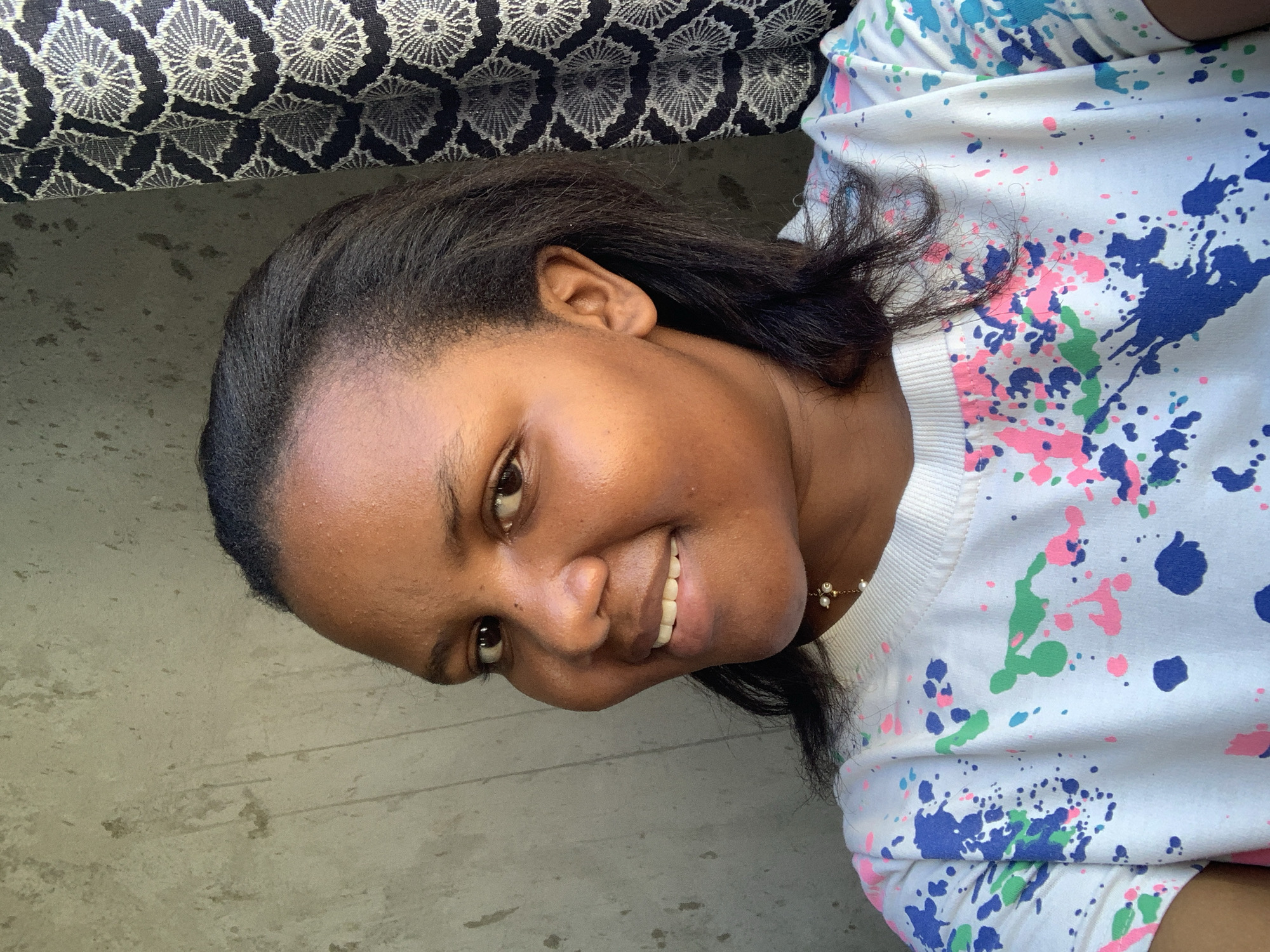 Woman in paint-splattered shirt photographed smiling in Dar es Salaam