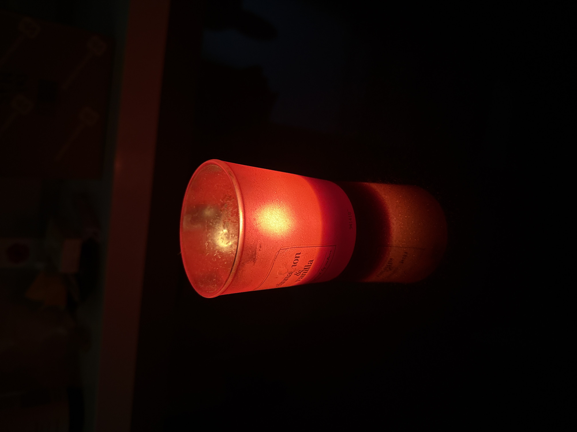 Red votive candle glowing on a dark countertop at home