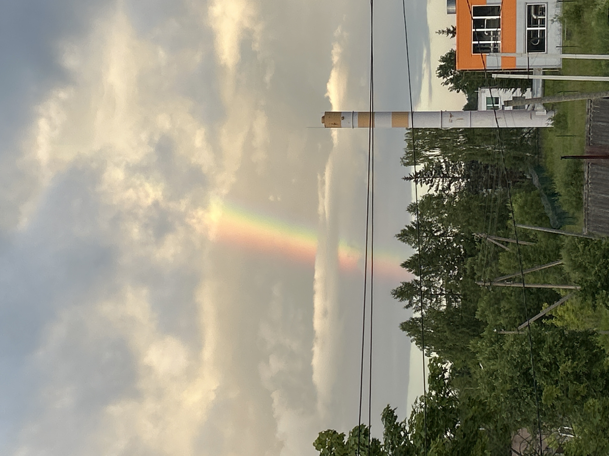 Rainbow over a striped industrial chimney in rural Russia
