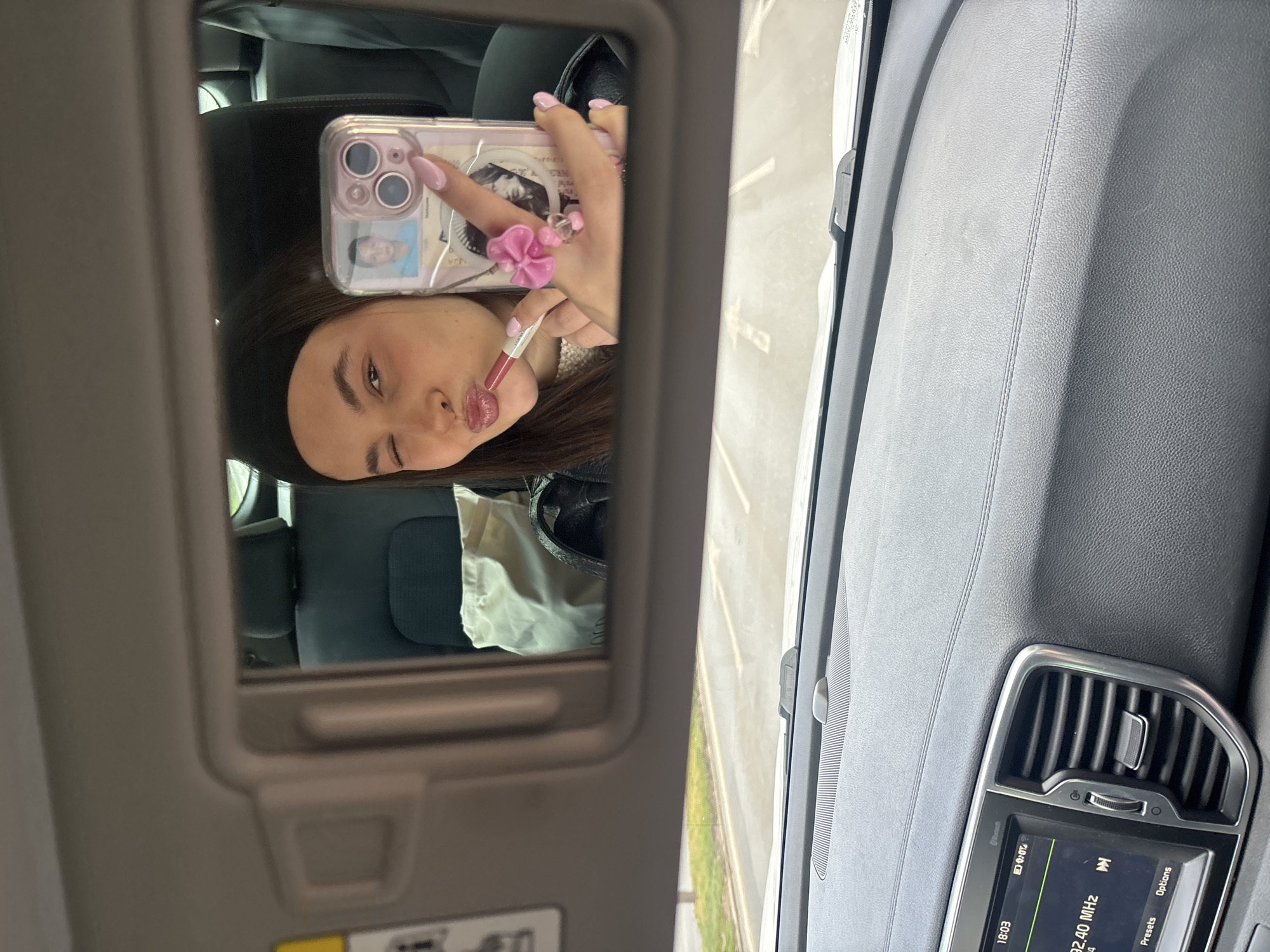 Woman Takes Selfie While Applying Makeup in Car Mirror