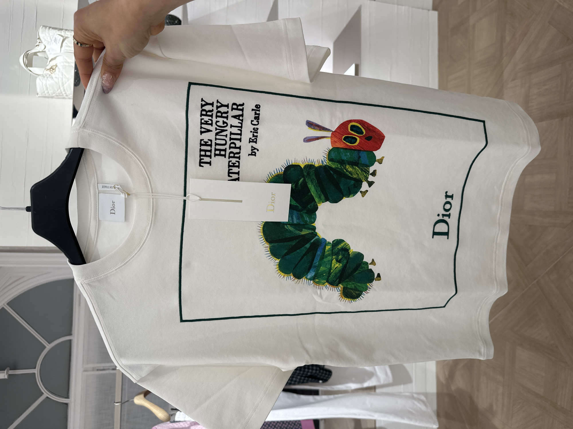 Person examines white graphic t-shirt in London retail store