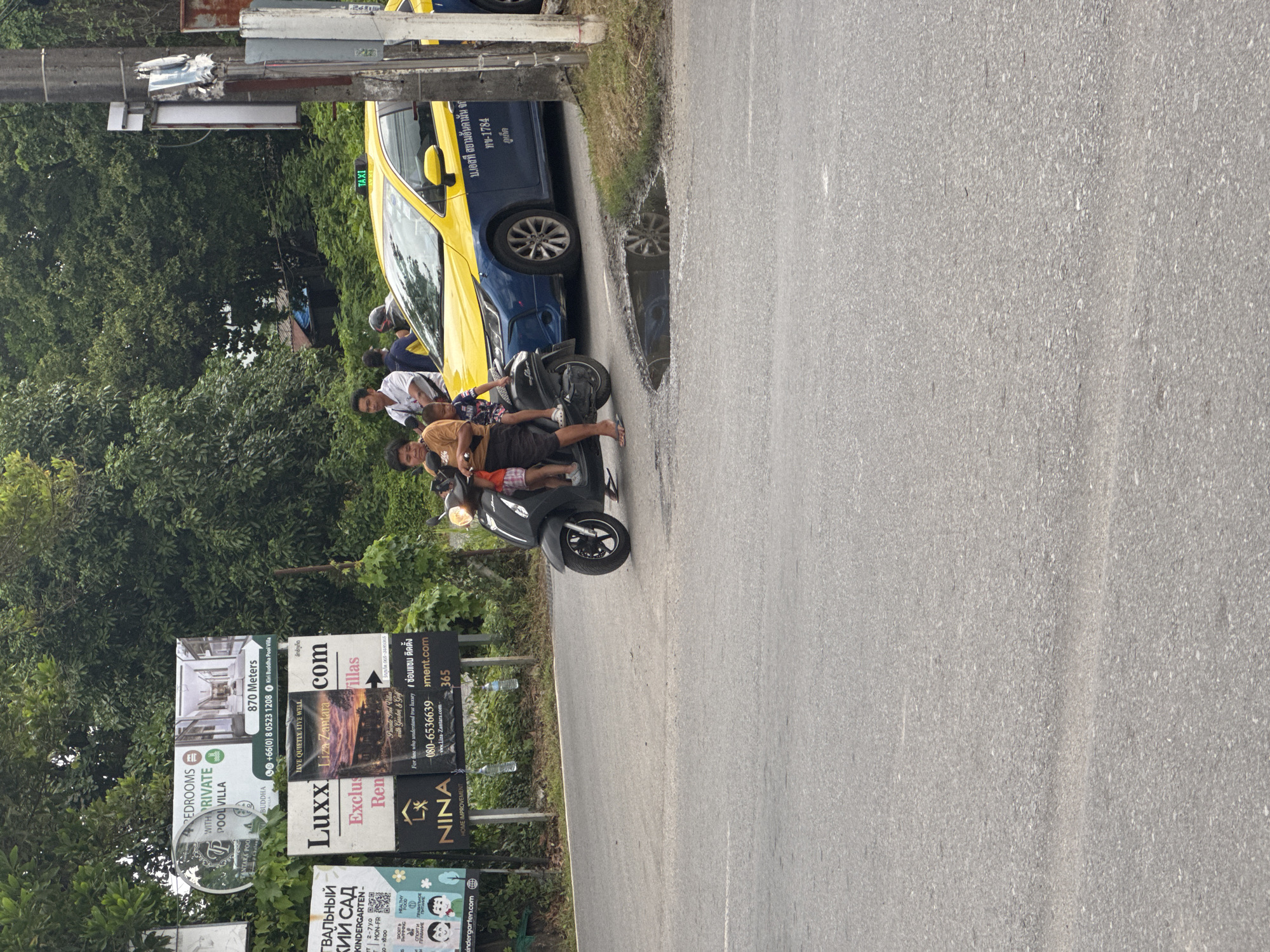 Motorcycles gather on Chalong road with delivery rider present