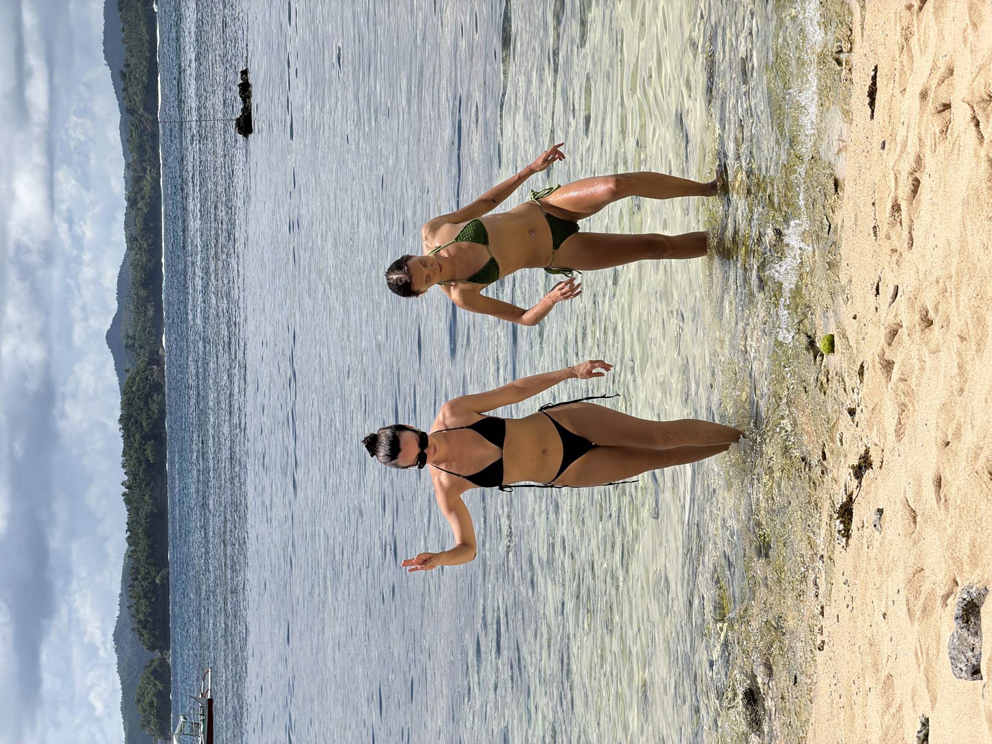 Two women pose in bikinis at General Luna beach