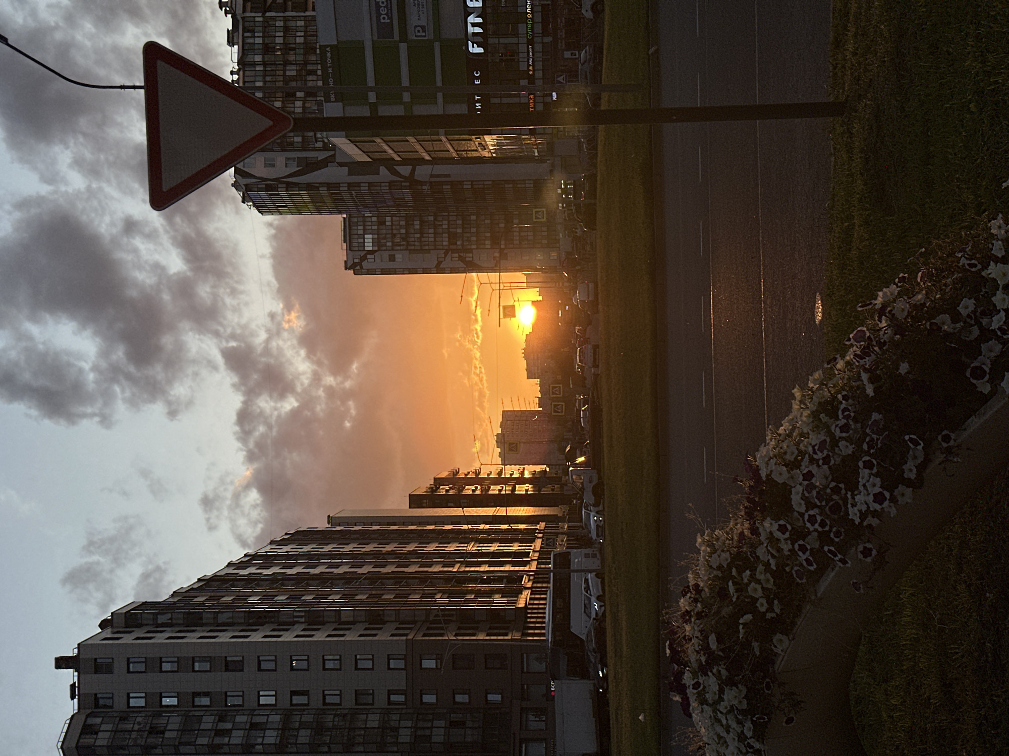 Sunset light breaks over a Kudrovo street in summer